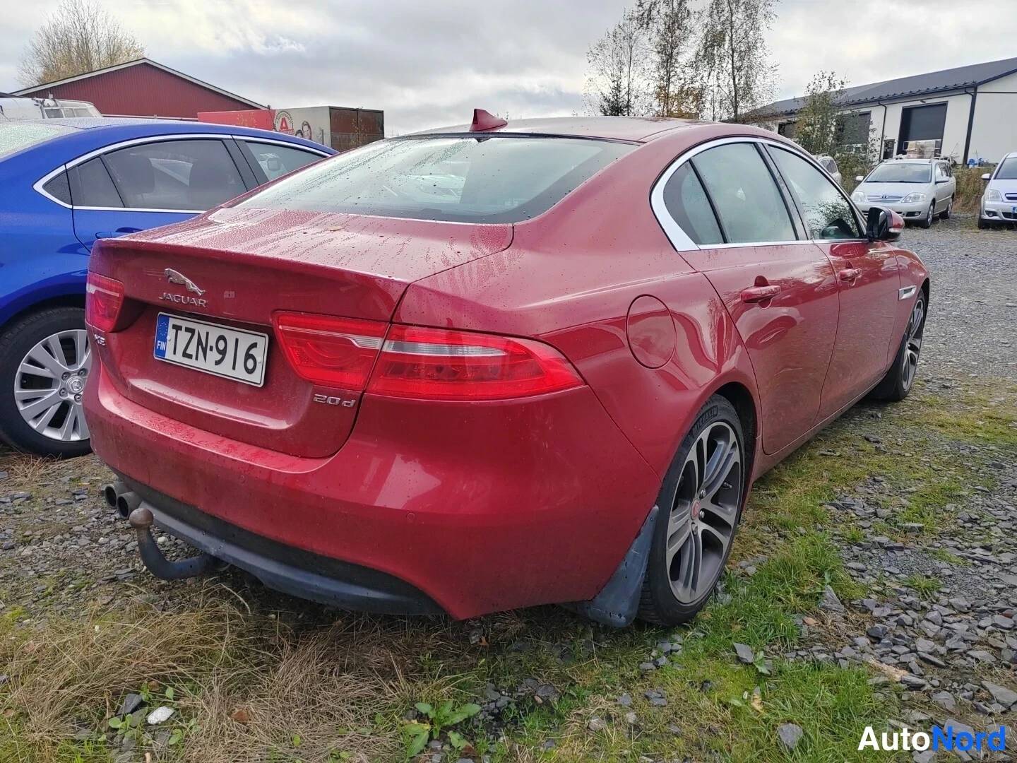 Takaviisto: Punaisen sedanin takakulma; takavalot, JAGUAR-tunnus, 20d-merkintä ja vetokoukku näkyvät lähikuvassa.