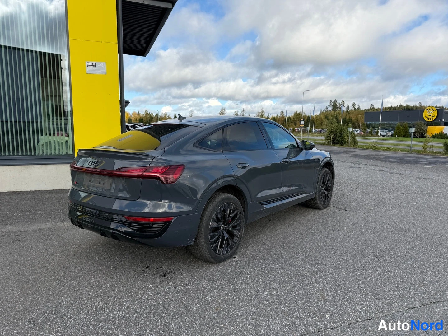 Takaviisto: Graysävyinen SUV kuvasi takaa ja kulmasta, takana näkyvät takavalot ja takaluukku