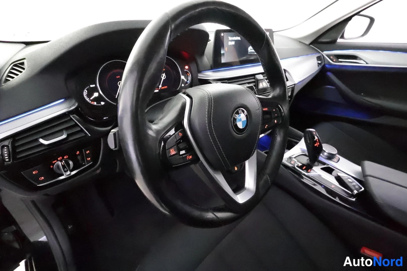 Yksityiskohta: Ohjaamo kuljettajan puolelta: BMW-merkkinen ohjauspyörä, mittaristo, keskikonsolin näyttö ja automaattivaihteen valitsin.