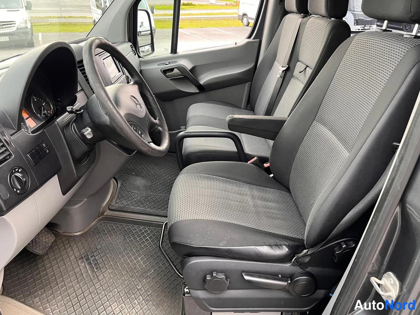 Ohjaamo: Fotografi av cabin visande förarens och passagerars stolarna, ratten, instrumentpanel och dörrpaneler. Vänsterdörr är öppen.
