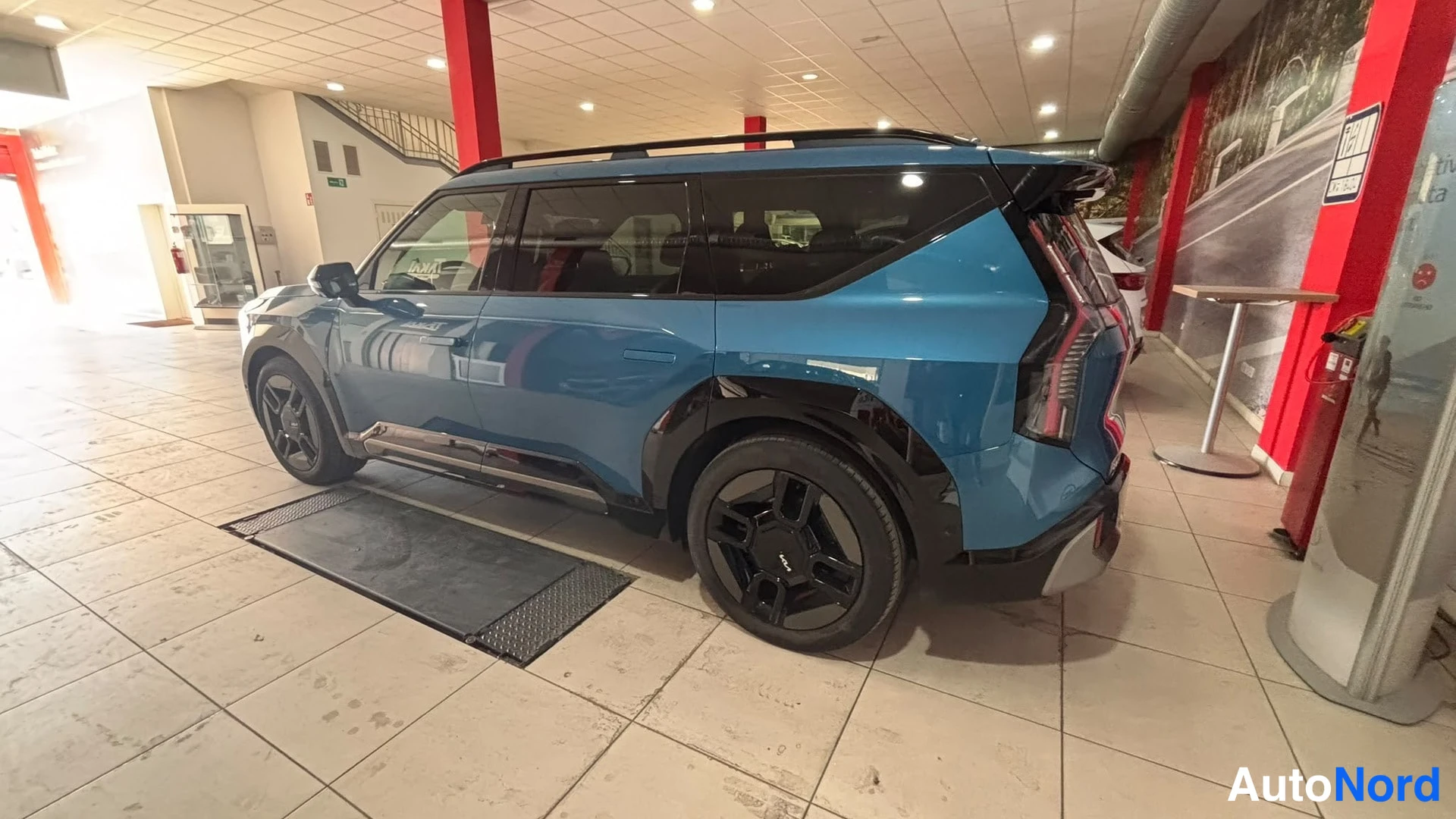 Sivulta: Kylkikuva sinisestä SUV:sta, jossa näkyvät mustat pyörät ja katotelineet.