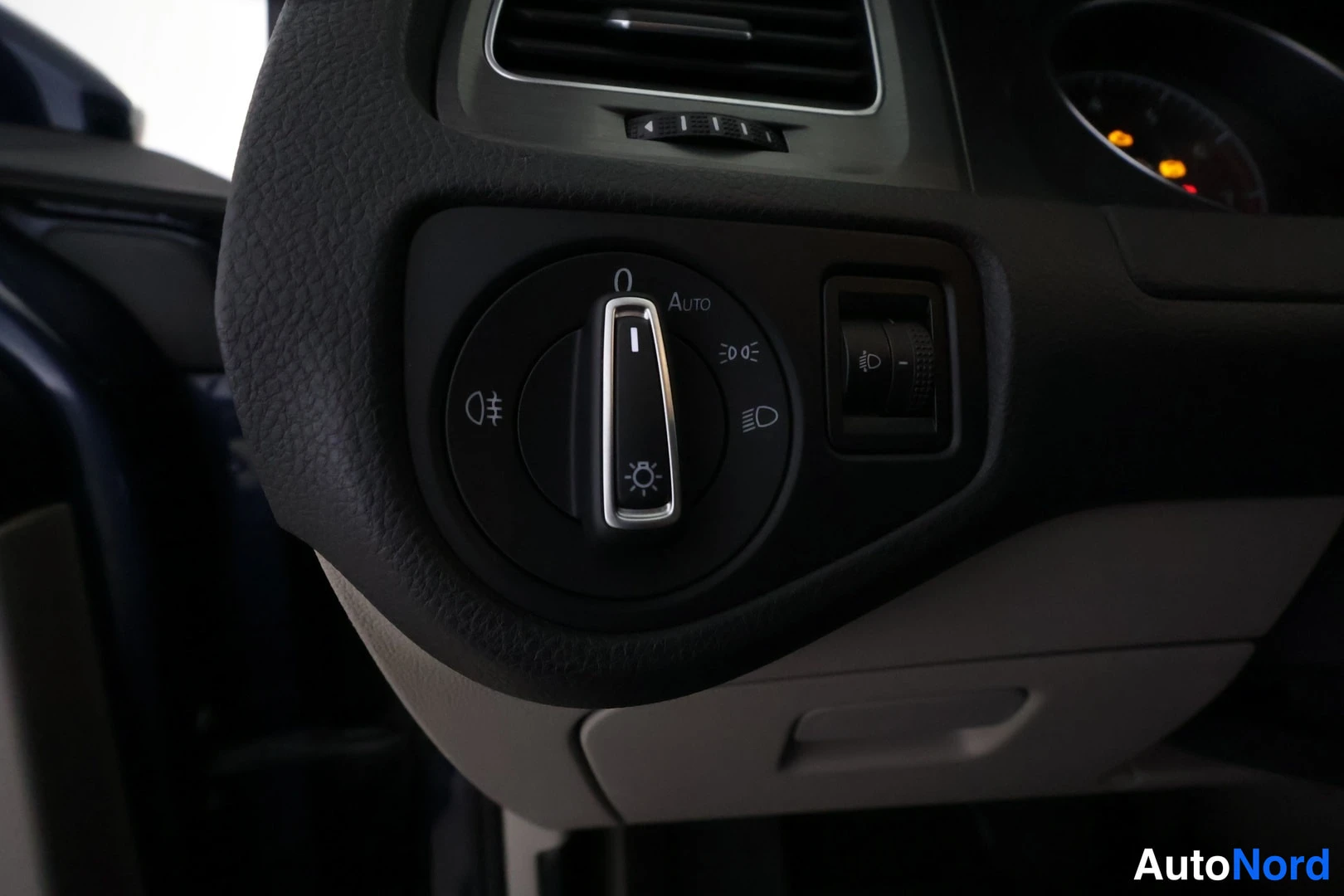Yksityiskohta: Sisätilakuvan lähikuva ohjaamon valokytkimestä, jossa AUTO-merkintä ja sumukykky.