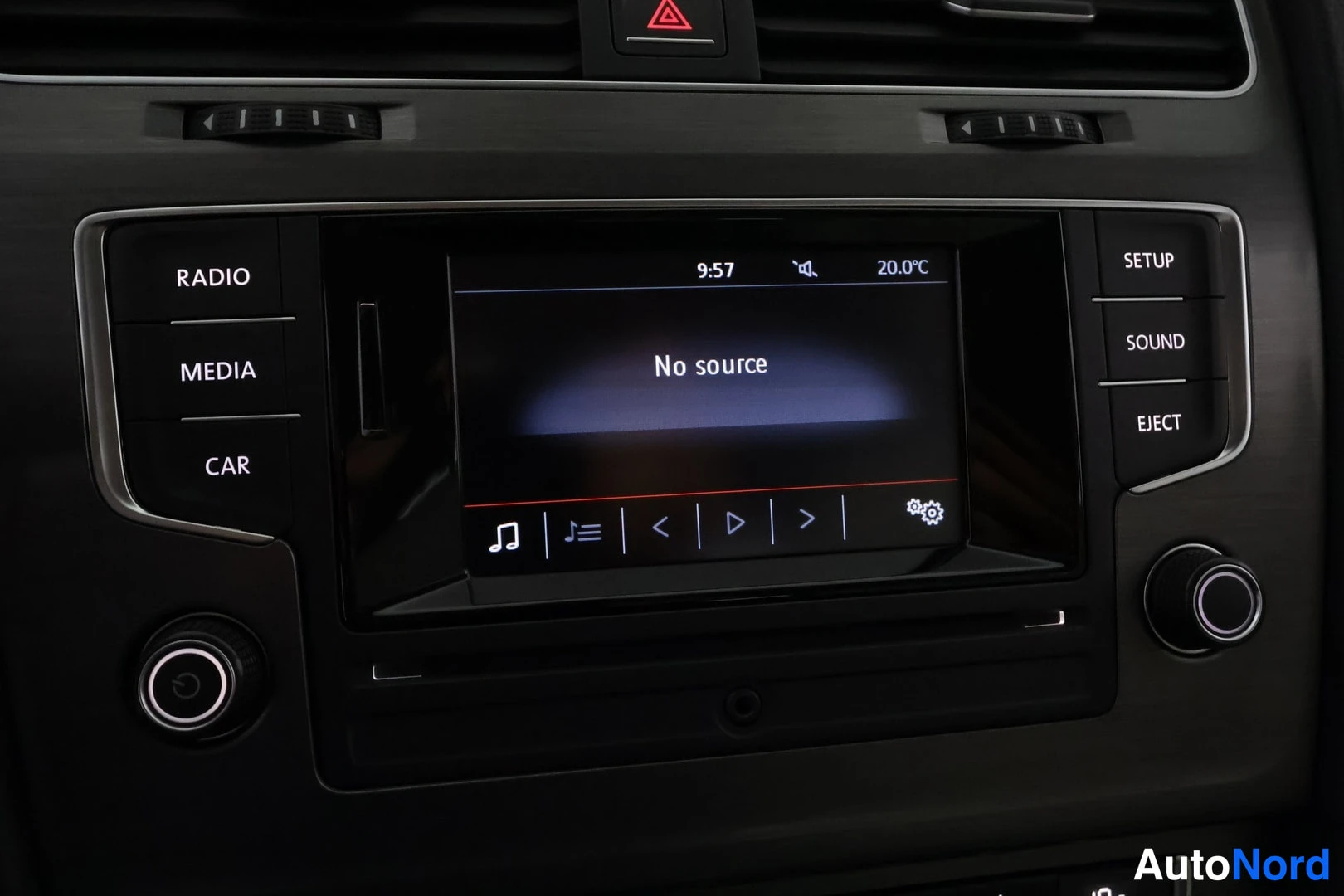 Muu: Kojelaudan keskikonsolin radionäyttö lähikuva, näytöllä teksti 'No source' sekä kellonaika 9:57 ja lämpötila 20,0 °C; AINO-näppäimet RADIO, MEDIA, CAR, SETUP, S