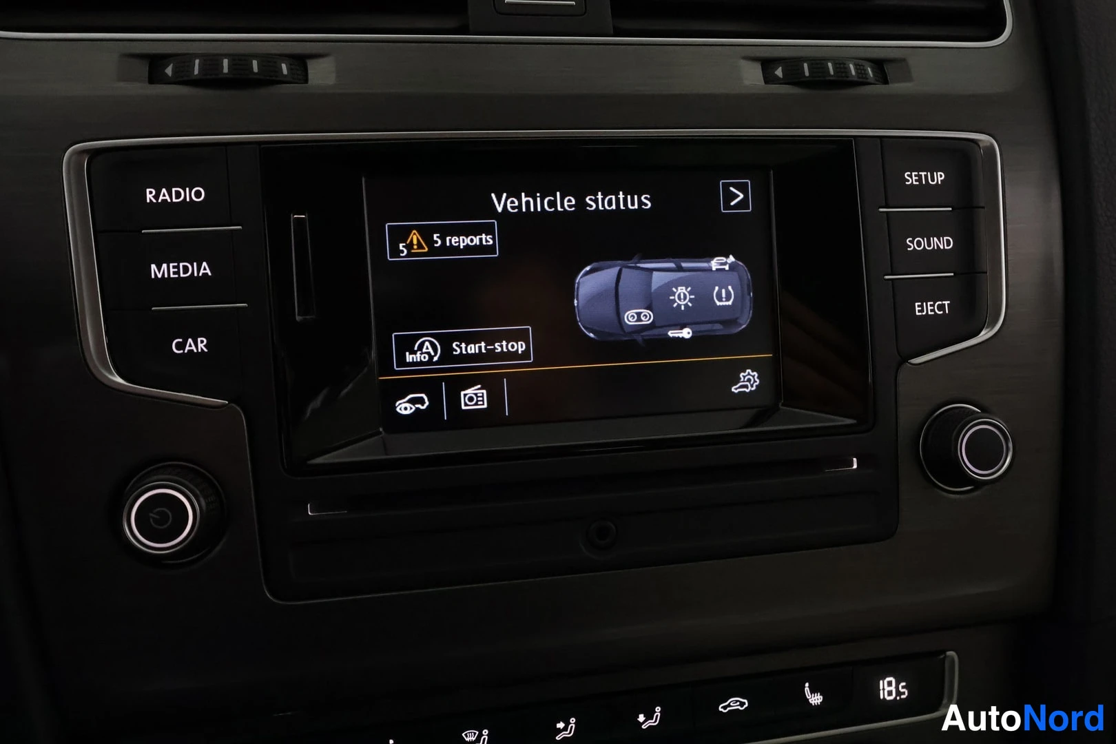 Muu: Keskikonsolin infotainment-näyttö lähikuva, näytöllä ajoneuvon tila -näkymä ('Vehicle status') auto-piktogrammineen, '5 reports' -merkintä ja 'Start-stop'-tekst
