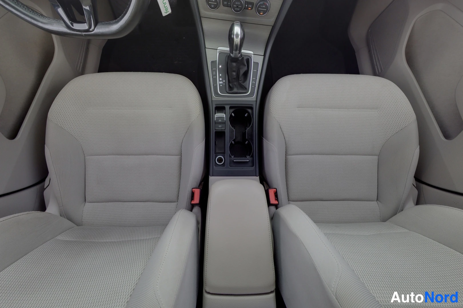 Etuistuimet: Front seats of a car with light beige fabric upholstery and a manual gear shift between them