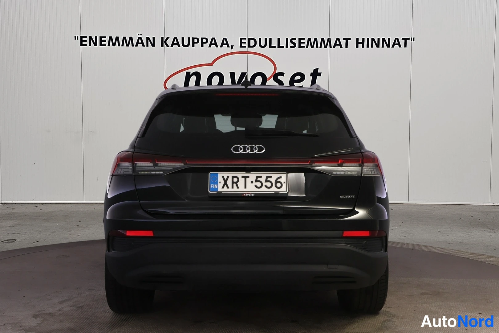 Takaa: Mustan Audi Q4:n suora takanäkymä, kokonaiset takavalot ja rekisteritunnus erottuvat.