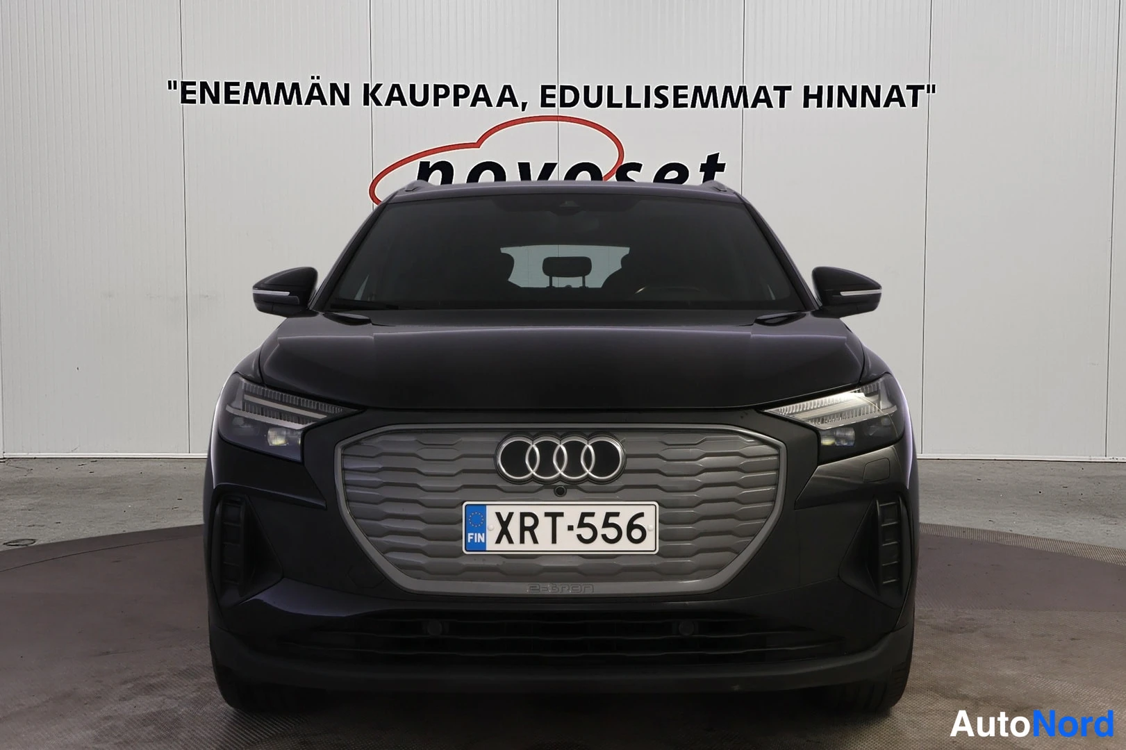Edestä: Mustan Audi Q4:n etupää suoraan edestä, masksa Audi-merkki ja rekisterikilpi.