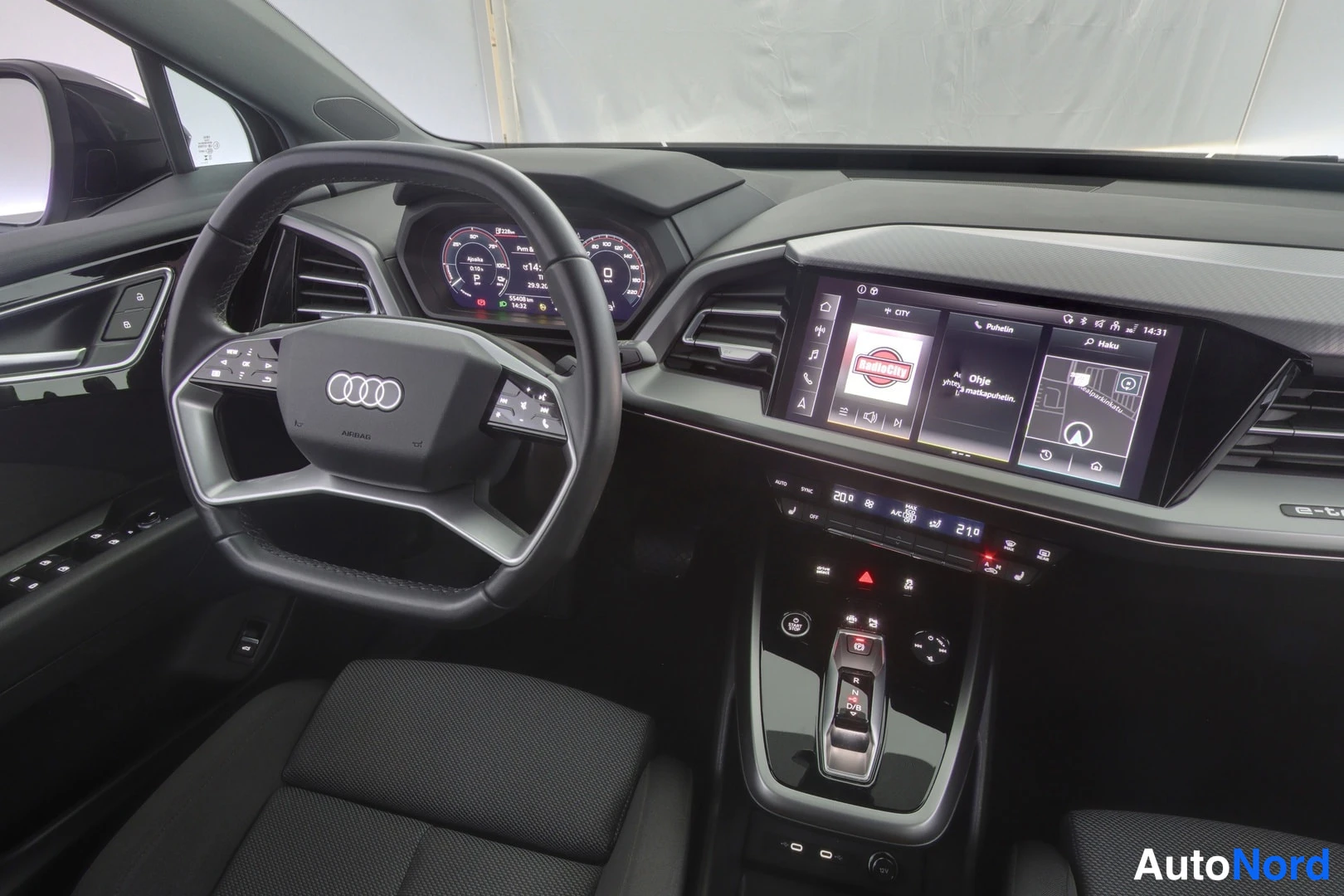 Edestä: Audi Q4:n ohjaamo lähemmin: ohjauspyörä, mittaristo, keskinäyttö ja keskiöconsole kauko-ohjaimineen.