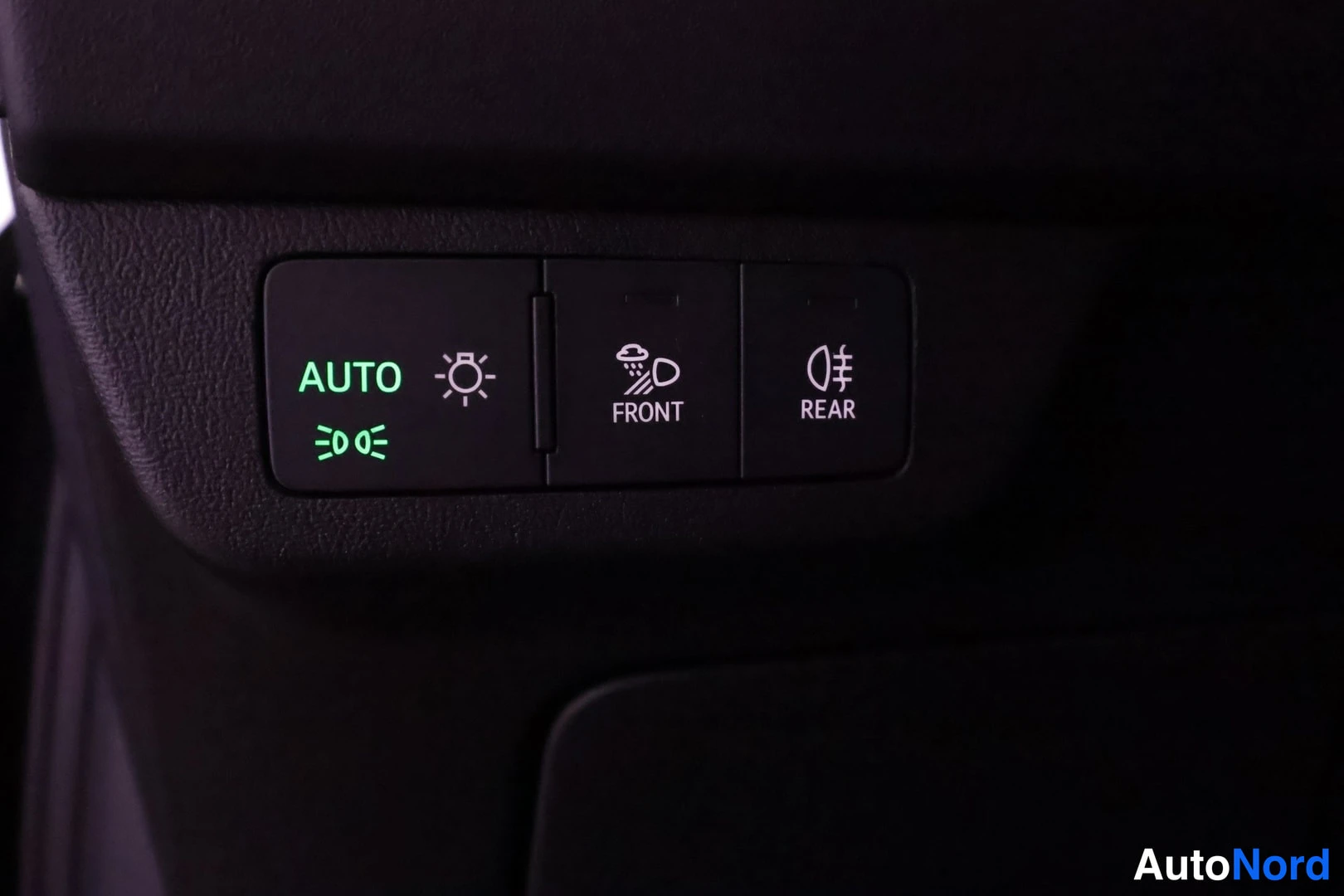Muu: Lähikuva valokytkinryhmästä: AUTO-merkintä, sumuvalo- ja valokuvio sekä FRONT- ja REAR-merkinnät tummassa paneelissa.
