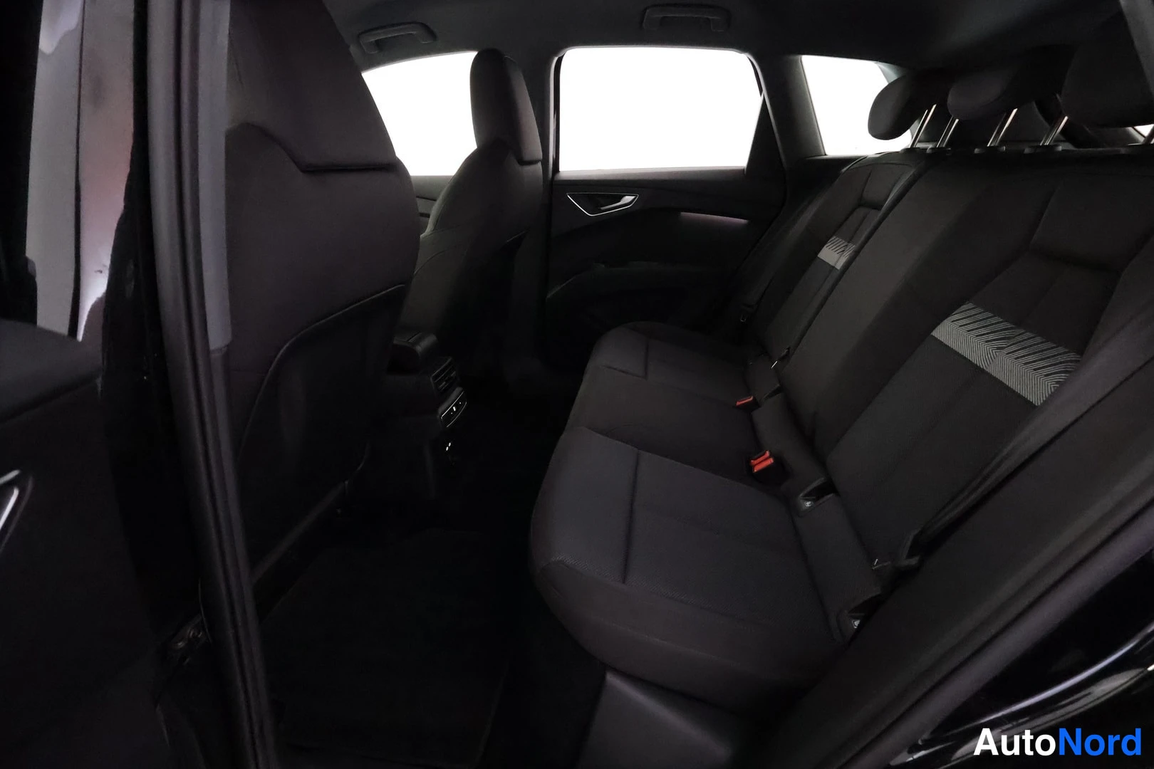 Sivulta: Audi Q4:n takapenkku ja tavaratilan sivut, tumma kangasverhoilu ja ovi auki näkyvät.