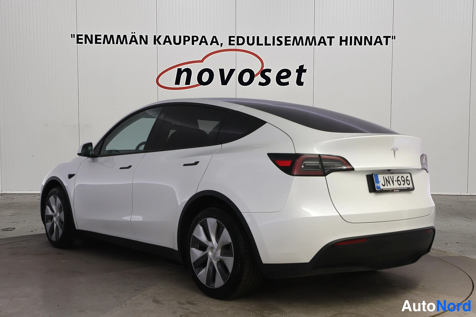Takaviisto: Valkoinen Tesla Model Y takakulmakuvassa, rekisterikilpi, studio-tausta.
