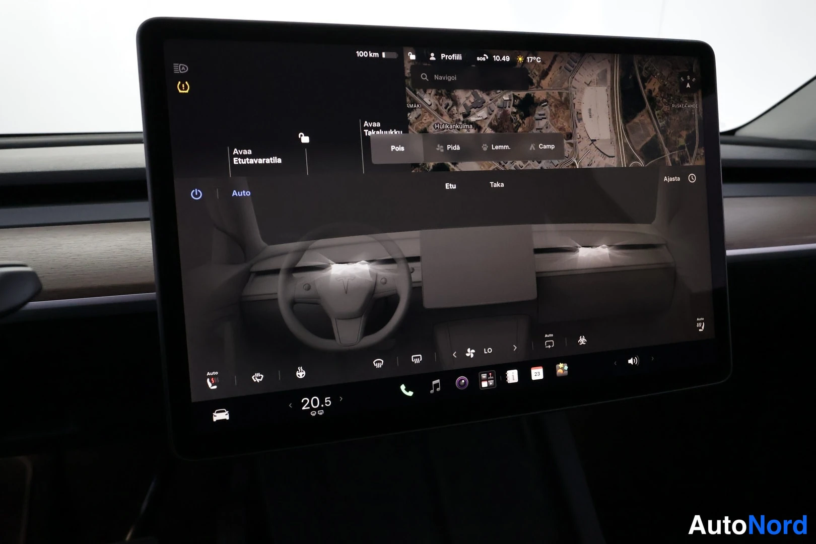 Yksityiskohta: Keskikonsolin suuri kosketusnäyttö, jossa näkyy Tesla-ohjelmiston käyttöliittymä satelliittikartta- ja ohjausnäkymällä.