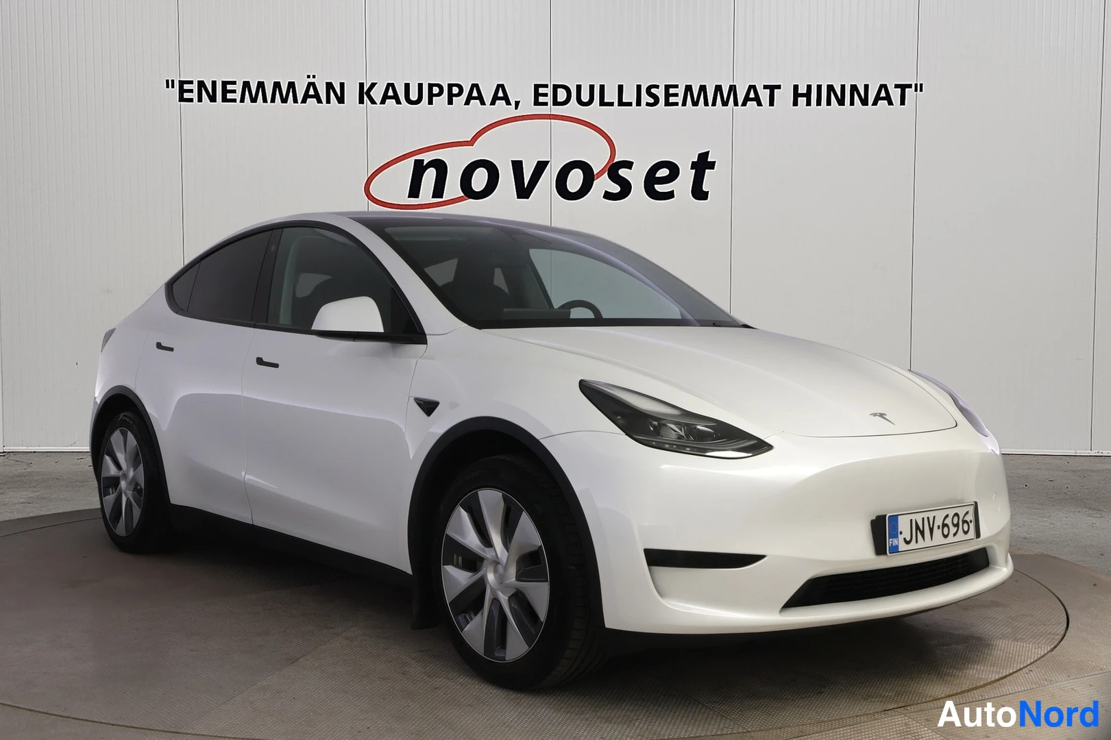 Etuviisto, nokka oikealle: Tesla Model Y -henkilöauto edestä oikealta kuvattuna, valkoinen koripinta, rekisterikilpi.