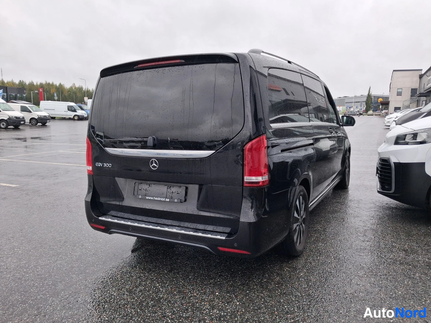 Takaviisto: Musta Mercedes-Benz EQV takaa suoraan viistosti oikealta, takaluukun lasi ja punaiset takavalot näkyvät, taustalla parkkipaikka ja muita autoja.