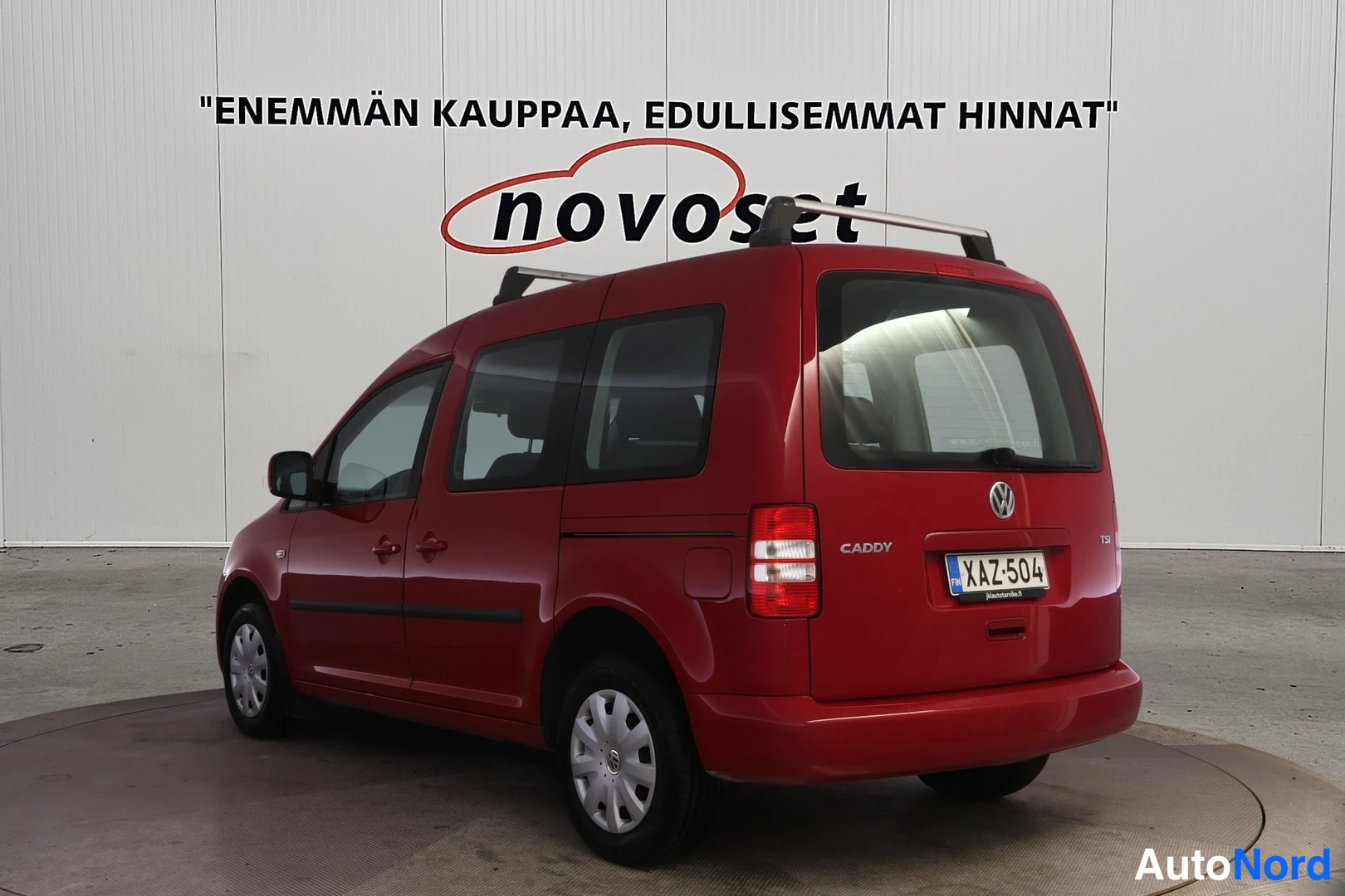 Takaviisto: Punainen Volkswagen Caddy takayläkulmasta, CADDY-teksti, takavalo ja -kilpi näkyvissä.
