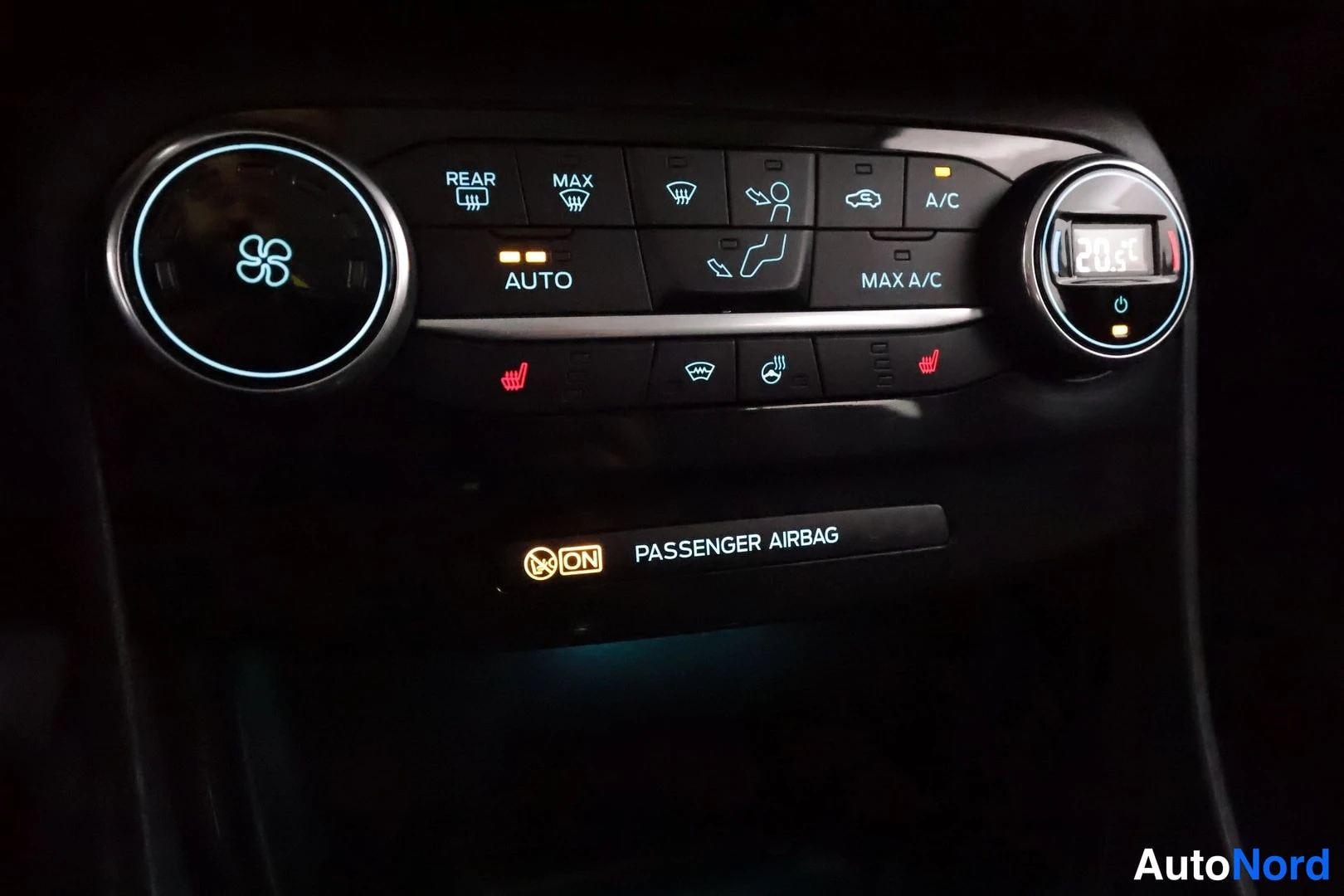 Yksityiskohta: Ilmastointilaitteen ohjauspaneeli: kaksi sinireunusteista säätökiekkoa, keskellä nappirivi teksteillä REAR, MAX, AUTO, A/C, MAX A/C ja lämpötilanäyttö 20.5, ala