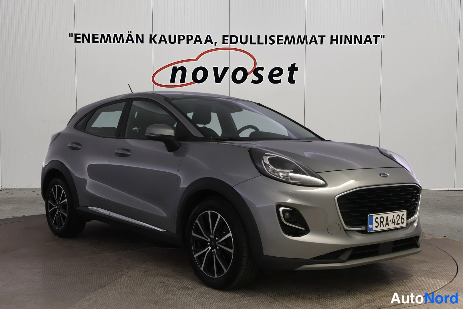 Etuviisto, nokka oikealle: Harmaa Ford Puma etuviistosta oikealta, rekisterikilpi, vaaleaa seinää vasten.