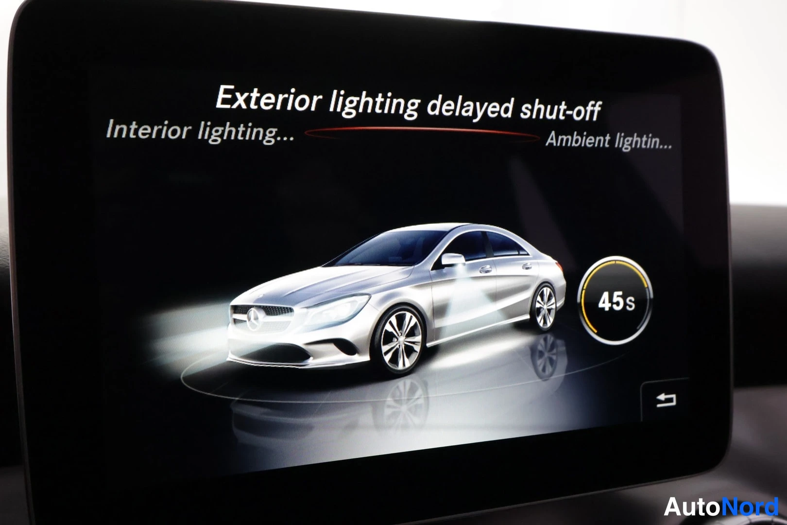 Yksityiskohta: Lähikuva auton infotainment-näytöstä, jossa valikko 'Exterior lighting delayed shut-off' ja ympyrävalitsin arvolla 45 s; alavalikot 'Interior lighting...' ja 'A