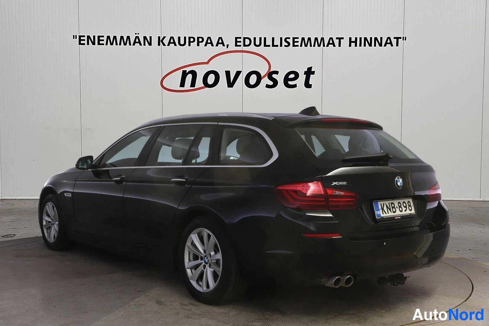 Takaviisto: Musta BMW 5-sarjan farmari takaa vasemmalta kolmesta neljänneksestä, takapanska ja kylki näkyvissä.