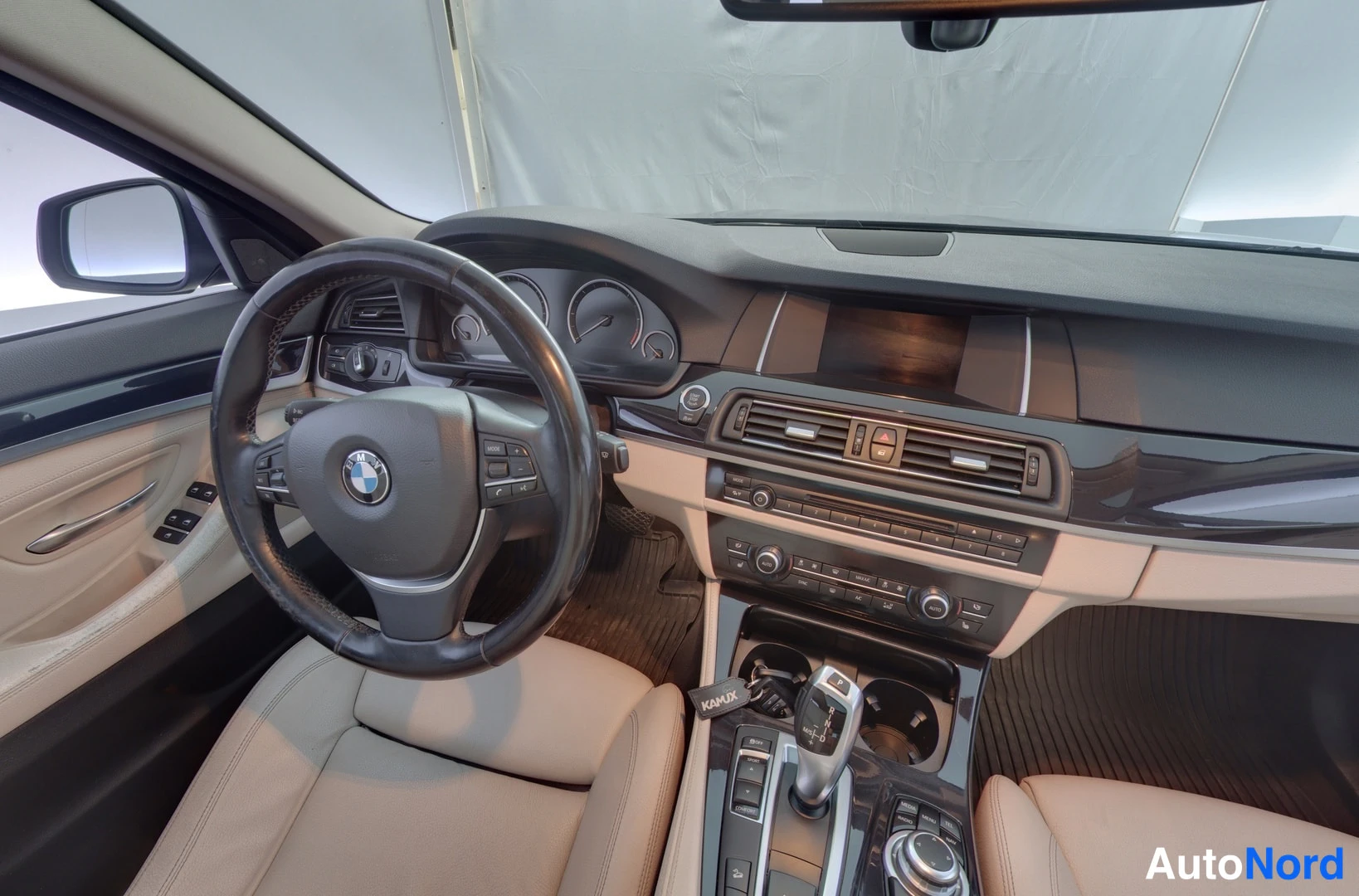 Etuistuimet: BMW'n sisätilan etuosa. Musta ohjauspyörä BMW-logolla, mittarit taustalla ja keskikonsoli automaattivaihtimella.