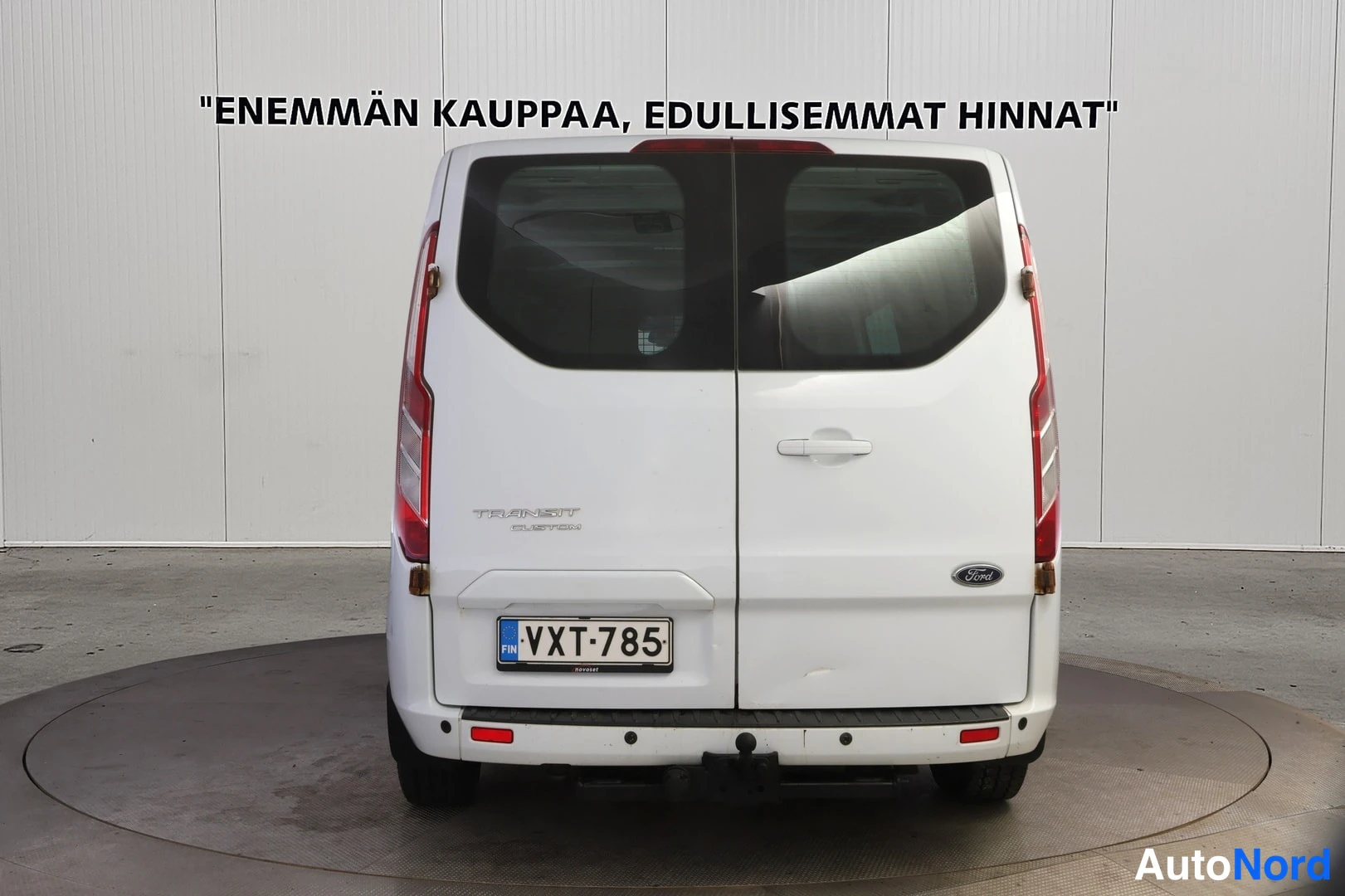 Takaa: Valkoinen Ford Transit Custom -pakettiauto suoraan takaa kuvattuna; kaksi peräoviä, Ford-merkki ja rekisteritunnus.
