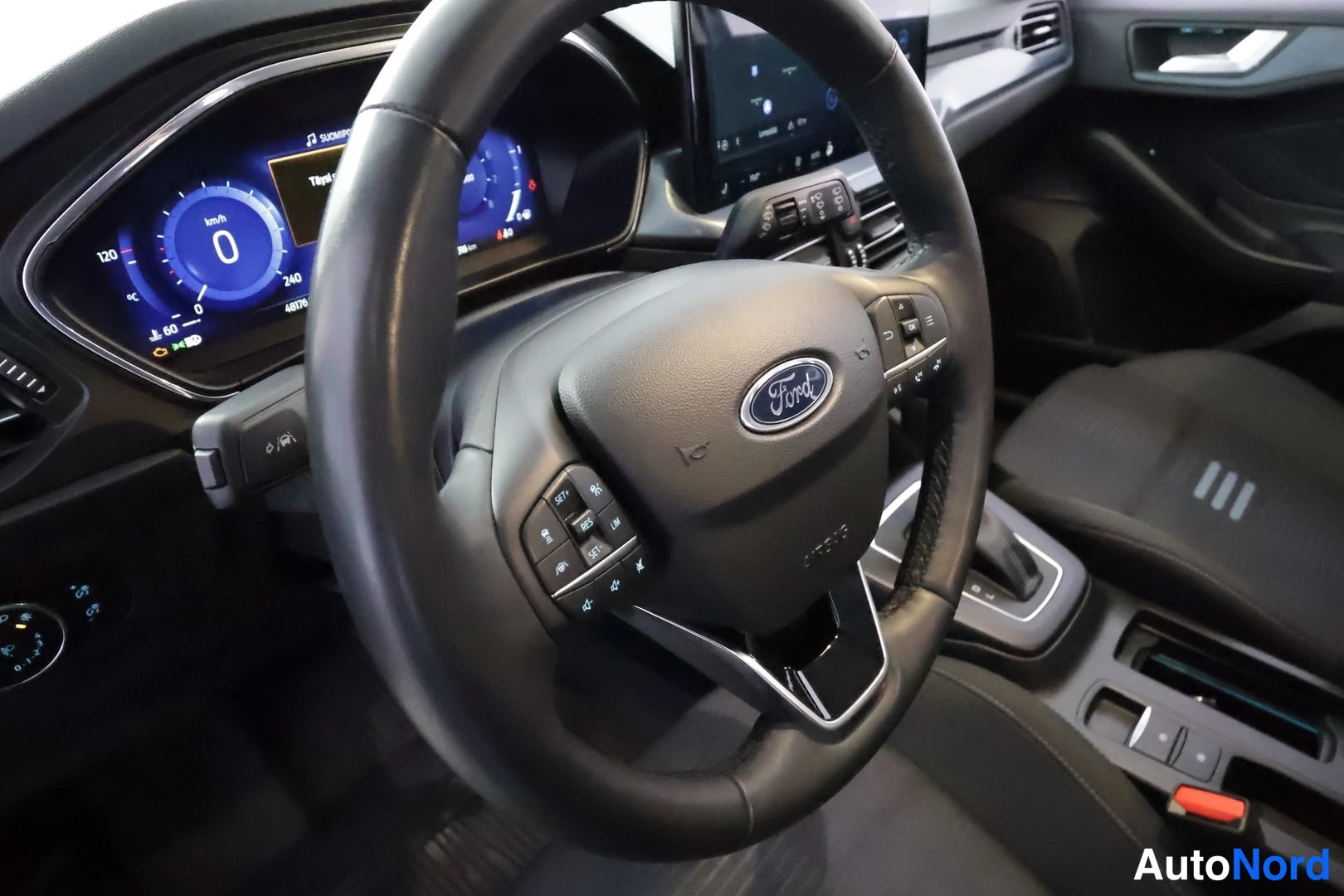 Muu: Ohjaamon näkymä Ford-merkkisellä ohjauspyörällä, mittaristolla ja keskikonsolilla.