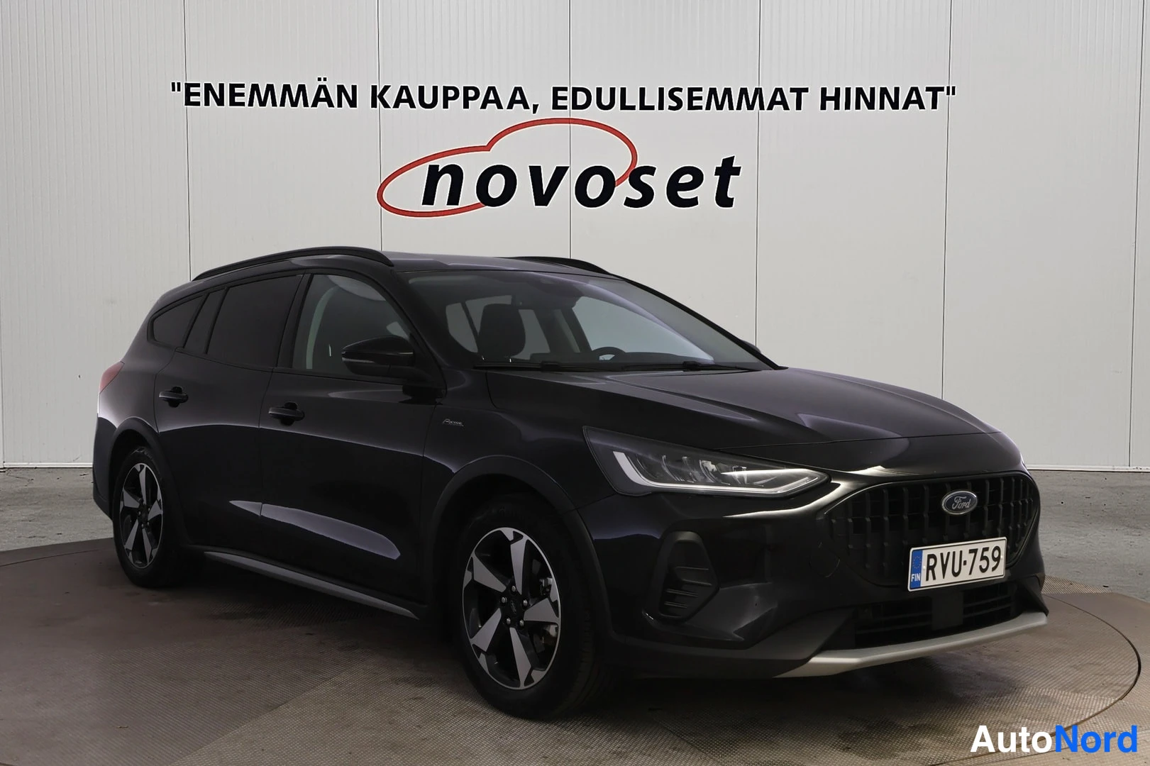 Etuviisto, nokka oikealle: Ford Focus Wagon in dark grey, shown from a front three-quarter angle displaying the left flank. Visible elements include the black grille, LED headlight