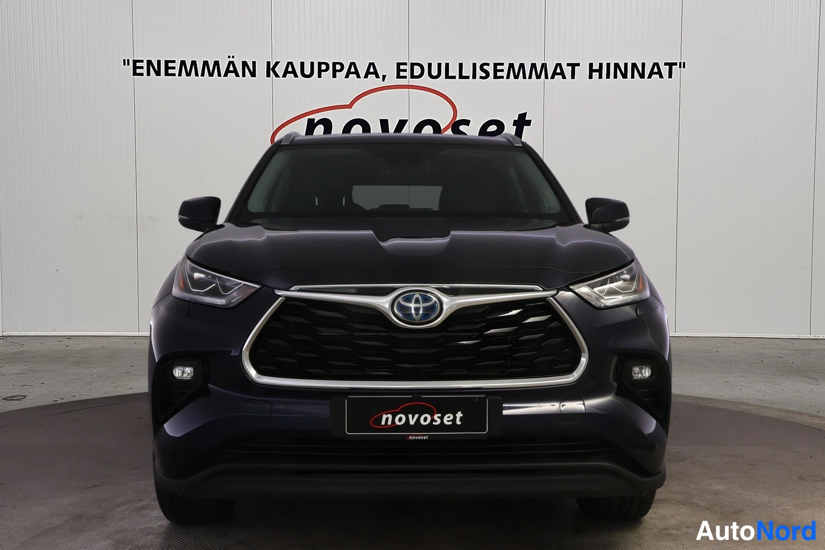 Edestä: Etukatselta kuvattu sinimusta Toyota Highlander, etusäleikkö ja valot keskellä kuvaa.