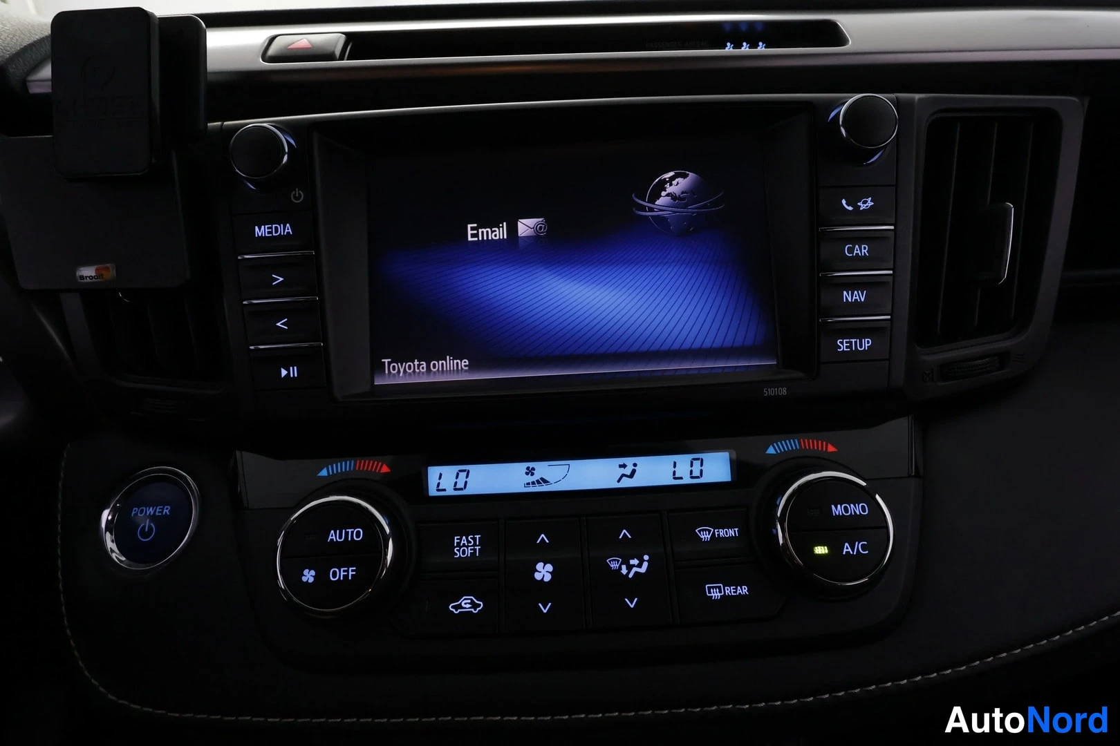 Muu: Kojeiston keskikonsoli: näytössä Toyota online -sähköpostinäkymä, NAV- ja SETUP-napit, alla ilmastointipaneeli.