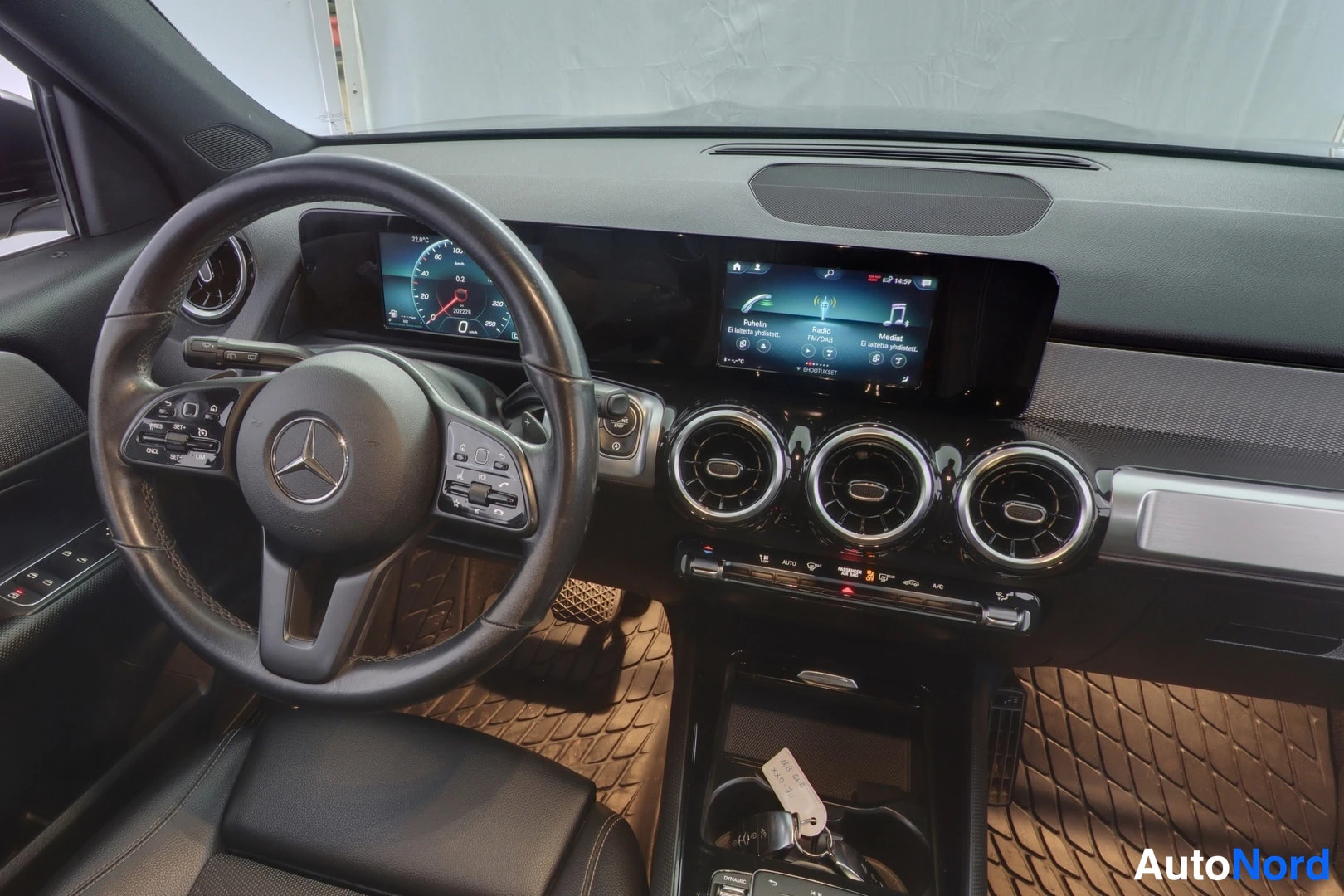 Muu: Mercedes-Benzin kojelauta lähikuvassa: ohjauspyörä, digitaalinen mittaristo, infotainment-näyttö ja kolme pyöreää suutinta.