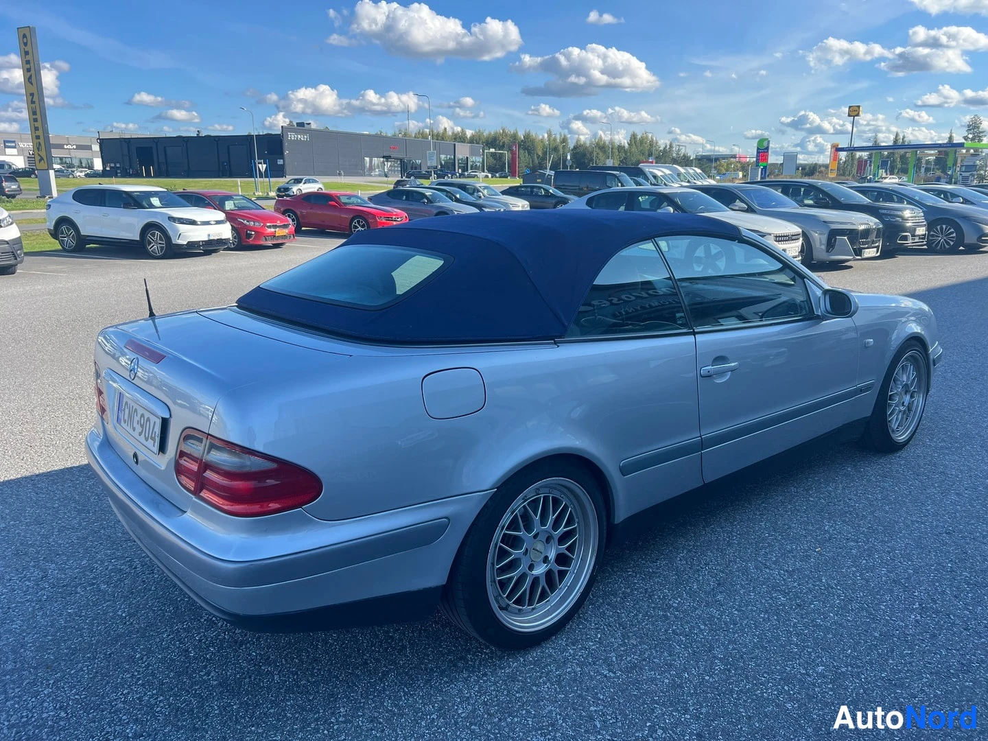 Takaviisto: Hopeansininen Mercedes-Benz CLK -avomalli tummansinisellä tekstiilikatolla kuvattuna takaosasta sivusuunnassa; punaiset takavalot, -kilpi ja hopeat moniavaravan