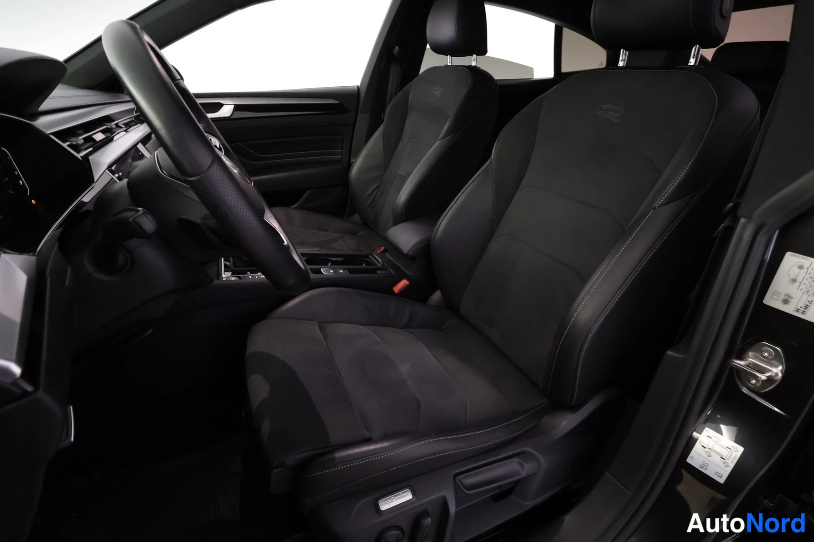 Ohjaamo: Close-up view of the black front bucket seats. The passenger seat features electric adjustment switches on its side, mounted below the seat cushion. The driver'