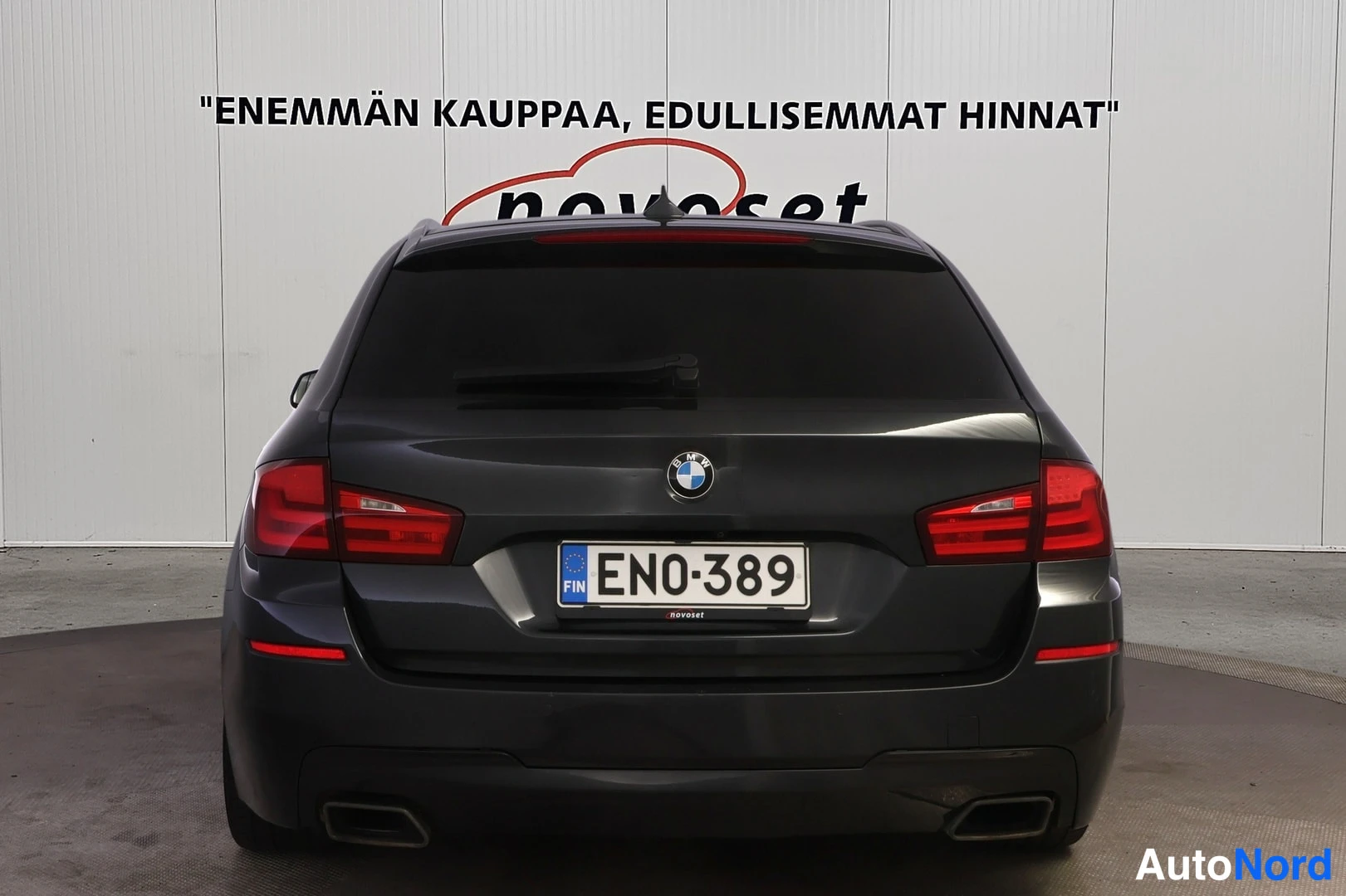 Takaa: Tummanharmaan BMW-farman suora takanäkymä; takaluukki, takavalot, kaksi pakoputkea ja rekisteritunnus näkyvät.