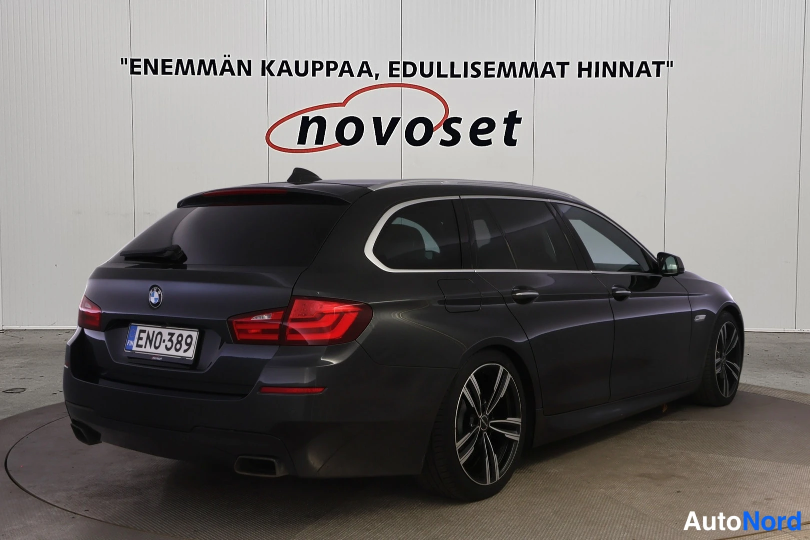 Takaviisto: Tummanharmaa BMW-farmari kuvattuna takakulmasta, perä vasemmalla; takaluukki, takavalot ja oikea kylki näkyvät, rekisteritunnus.