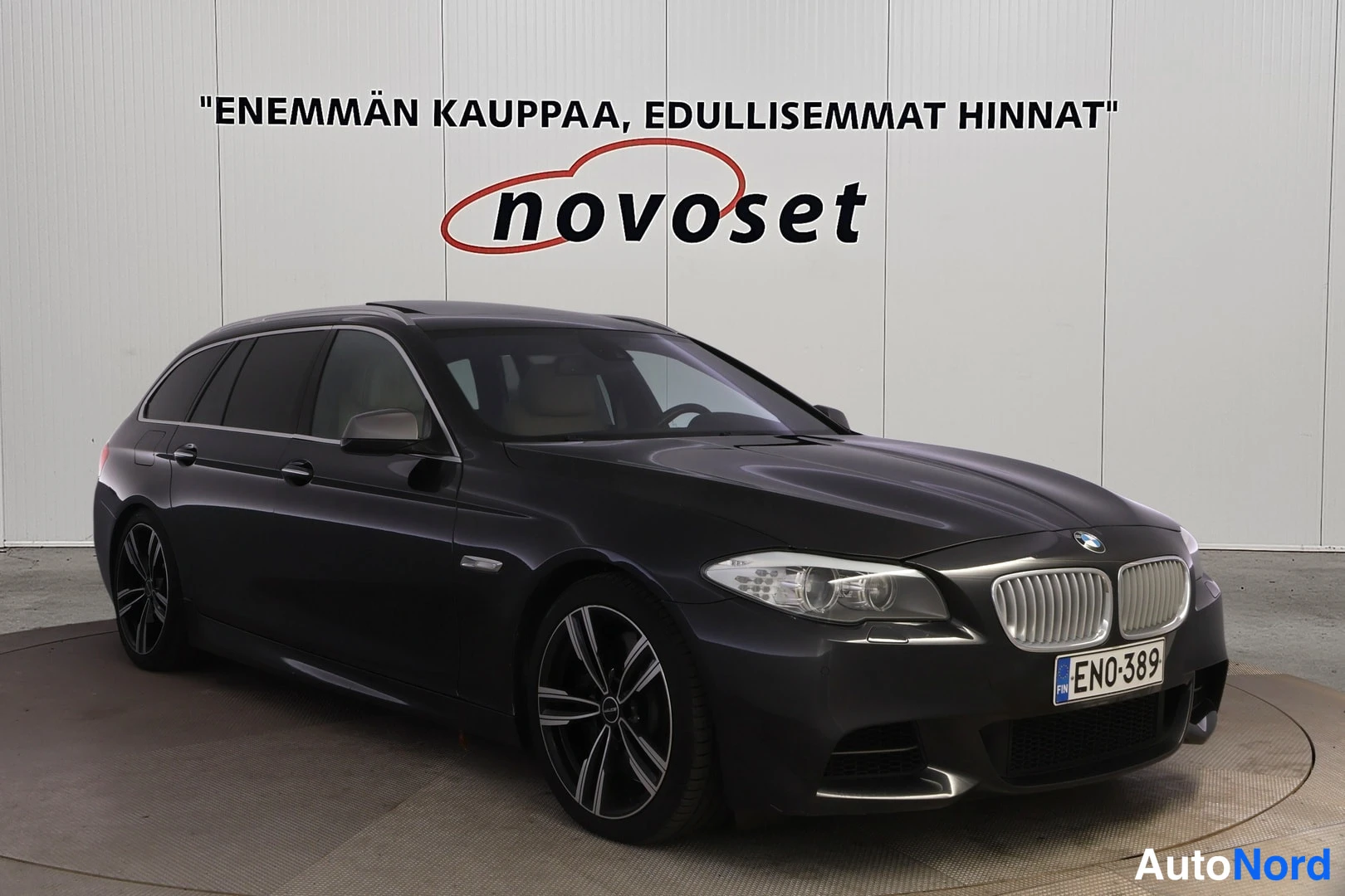 Etuviisto, nokka oikealle: Tummanharmaa BMW-farmari kolmen neljäsosan etunäkymässä keula oikealla; vasen kylki ja keula näkyvissä, rekisterikilpi.