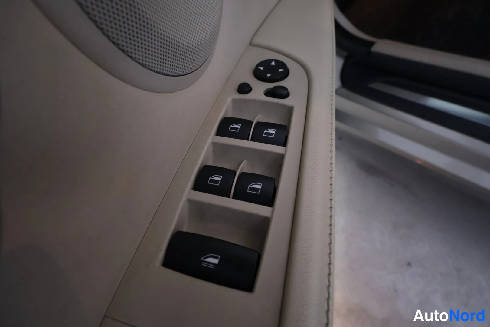 Yksityiskohta: Oven sisäpaneelin ikkunakytkimet ja peilinsäädön joystick vaaleassa oviverhoilussa.