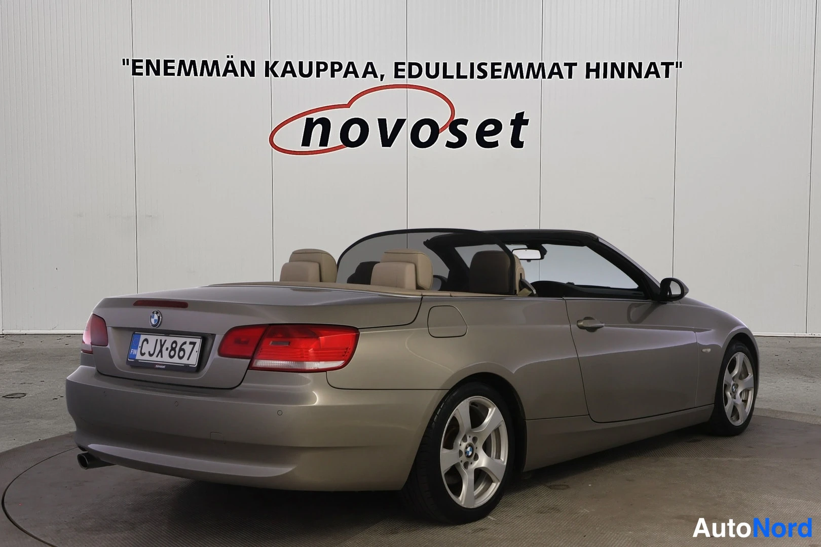 Takaviisto: Rear three-quarter view from the passenger side. The gold body paint, soft-top roof mechanism housing, and alloy wheels are visible. Tan interior headrests can