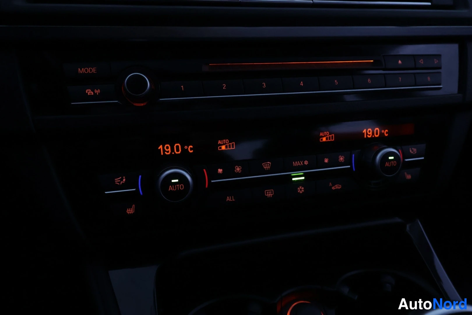 Yksityiskohta: Auton kojelaudan ilmastointipaneeli näyttää molempien osapuolten lämpötilaksi 19,0 °C, AUTO-tilassa, lähellä radiopainikkeita ja MODE-painiketta.