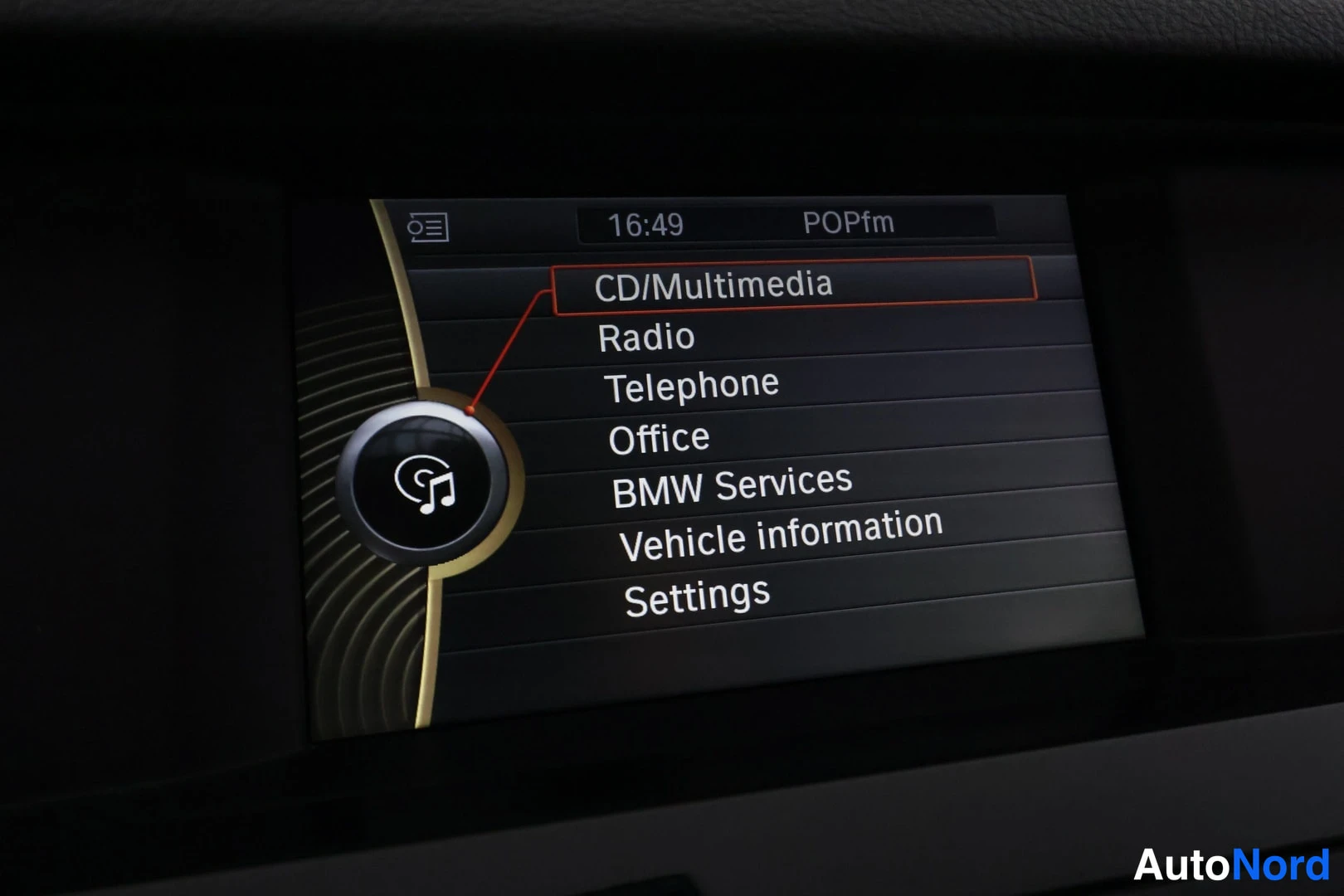 Yksityiskohta: Auton infotainment-näyttö listaa vaihtoehtoja: CD/Multimedia, Radio, Telephone, Office, BMW Services, Vehicle information ja Settings, kellonaika 16:49.