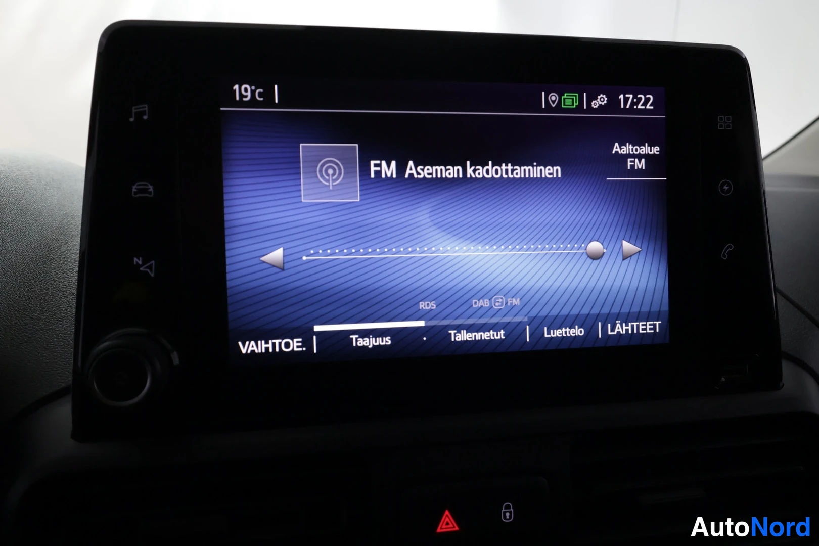 Muu: Auton kosketusnäyttö näyttää FM-radiovalikkoa, jossa lukee 'FM Aseman kadottaminen' ja alareunassa vaihtoehdot Taajuus, Tallennetut, Luettelo ja LÄHTEET.