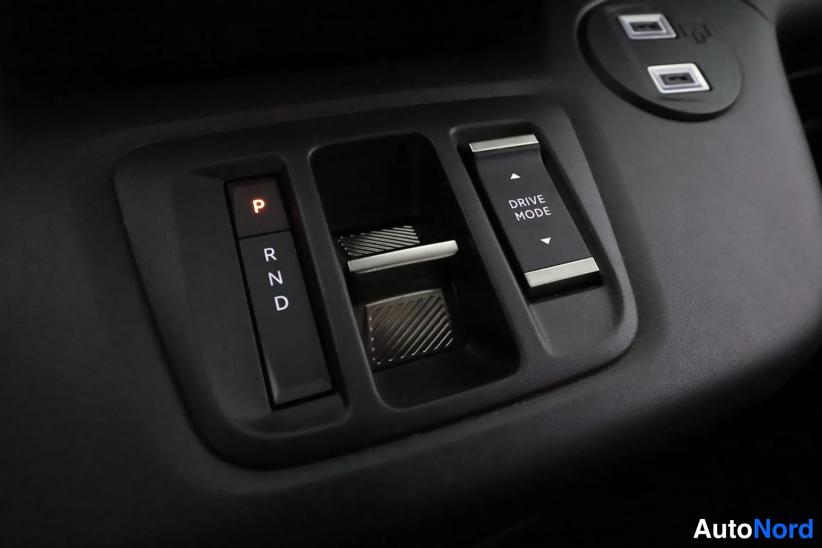 Muu: Tummansininen valintakytkin P-R-N-D ja DRIVE MODE-vipu keskikonsolissa
