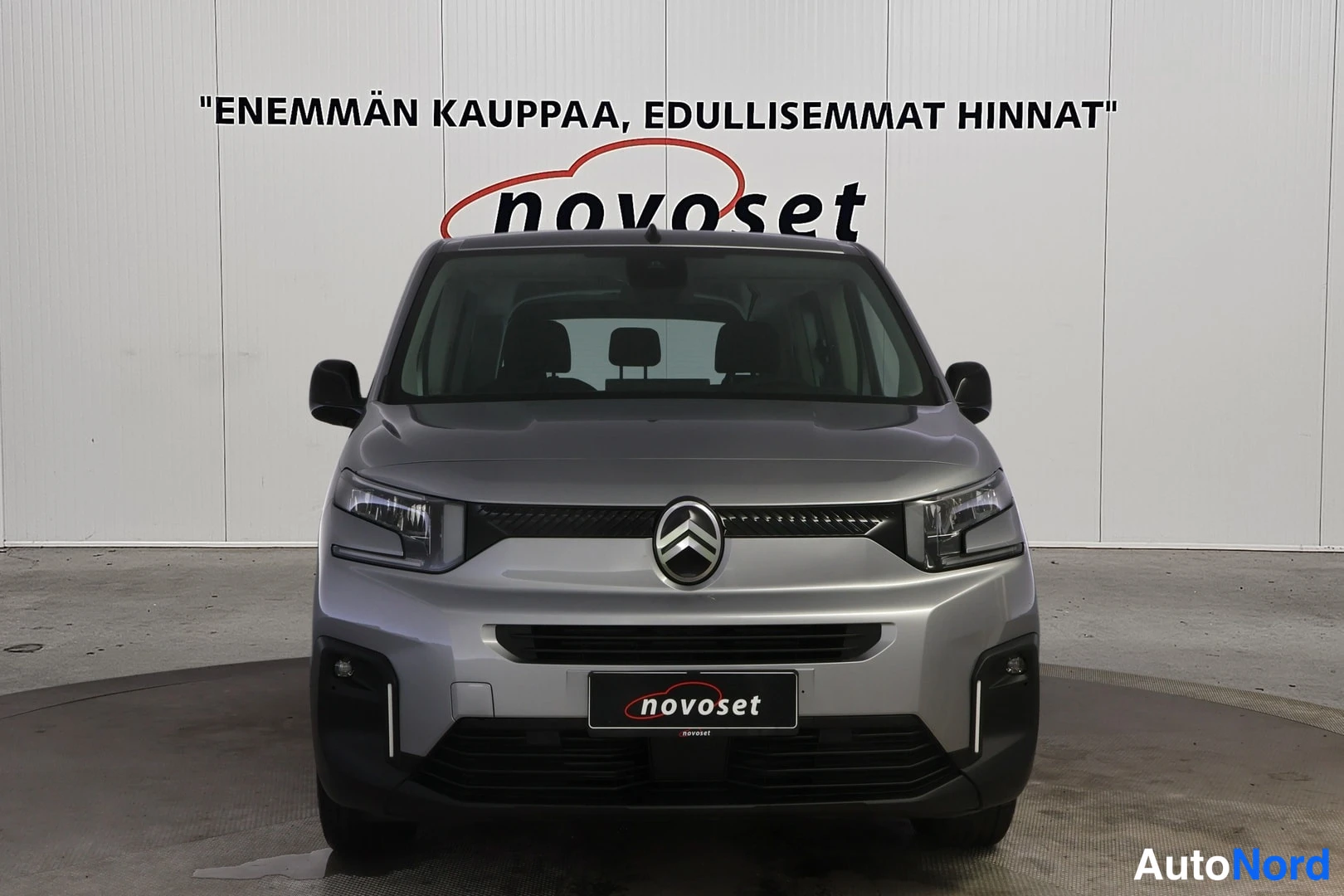 Edestä: Straight-on frontal view of a silver Citroen van featuring the grille, central logo, headlights, and lower black bumper trim.