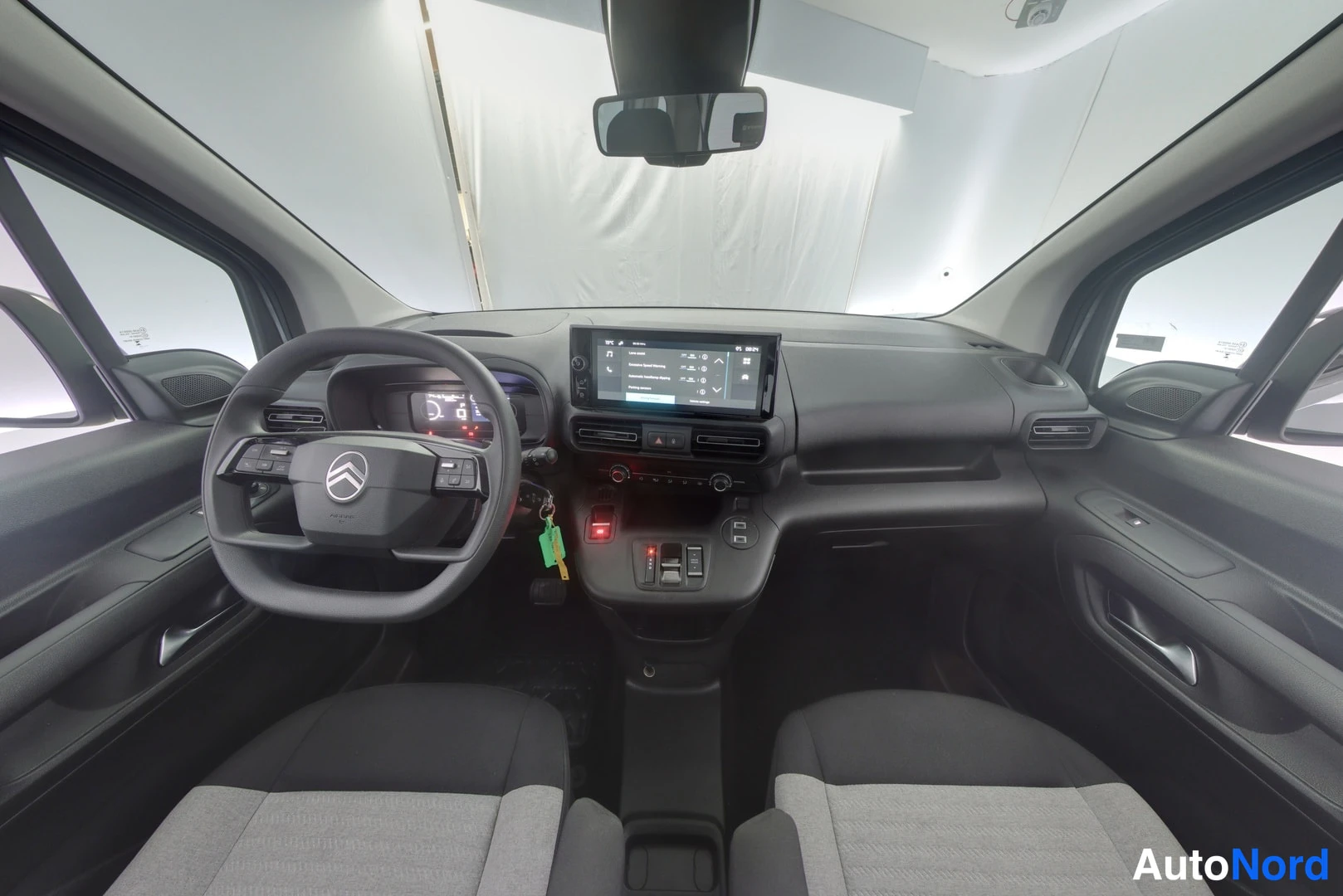Ohjaamo: Cabin interior shot from the rear seat position looking forward, displaying two front seats, dashboard layout with digital instrument cluster, touchscreen infot