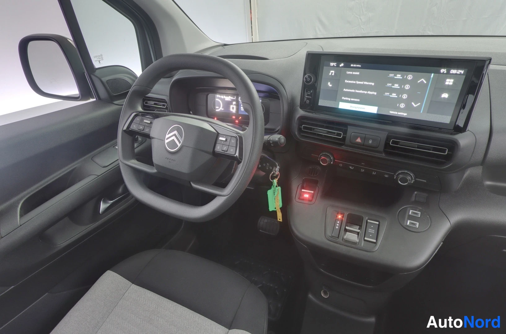 Ohjaamo: Interior left-side view focusing on the driver area: steering wheel with buttons, digital instrument cluster, center console with touchscreen navigation, climat