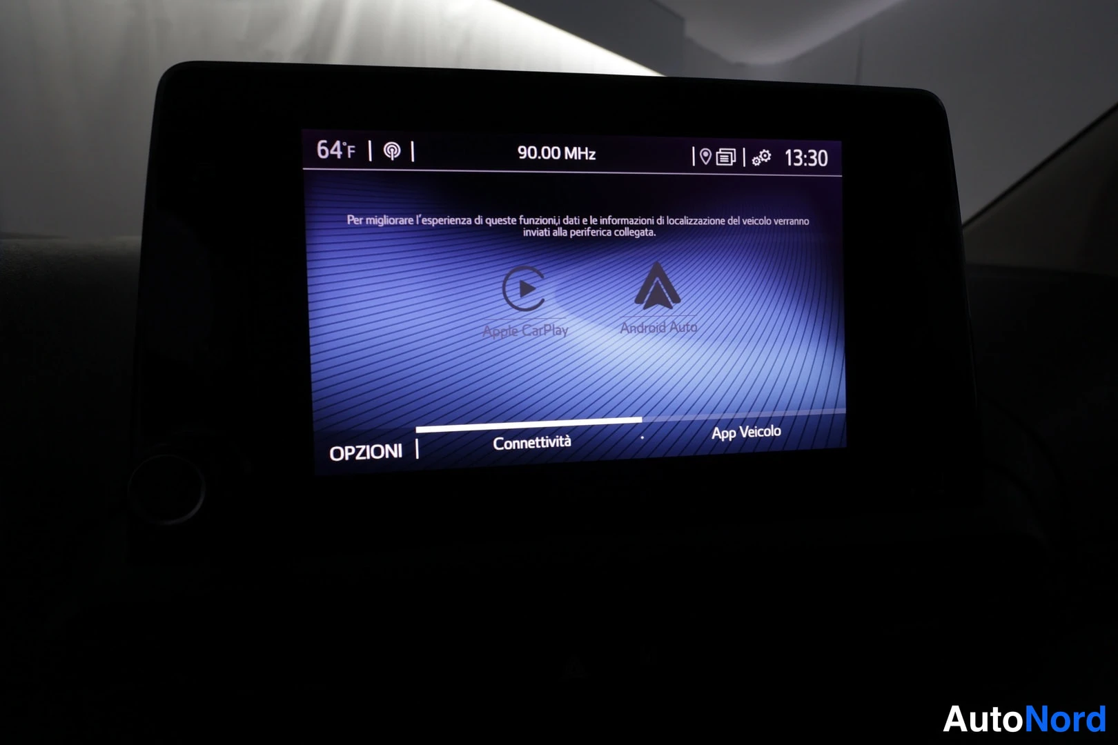 Muu: Kojelaudan kosketusnäyttö, jossa näkyy radio 90.00 MHz ja liitettävyysnäkymä Apple CarPlay- ja Android Auto-kuvakkeineen sekä tekstit OPZIONI, Connettività ja A