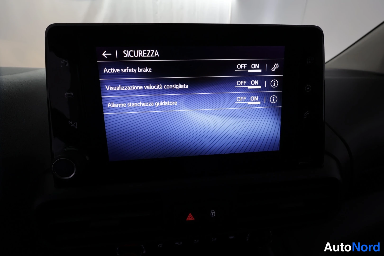 Yksityiskohta: Infotainment-näytön SICUREZZA-valikko, jossa Active safety brake -toiminto on ON-asennossa.