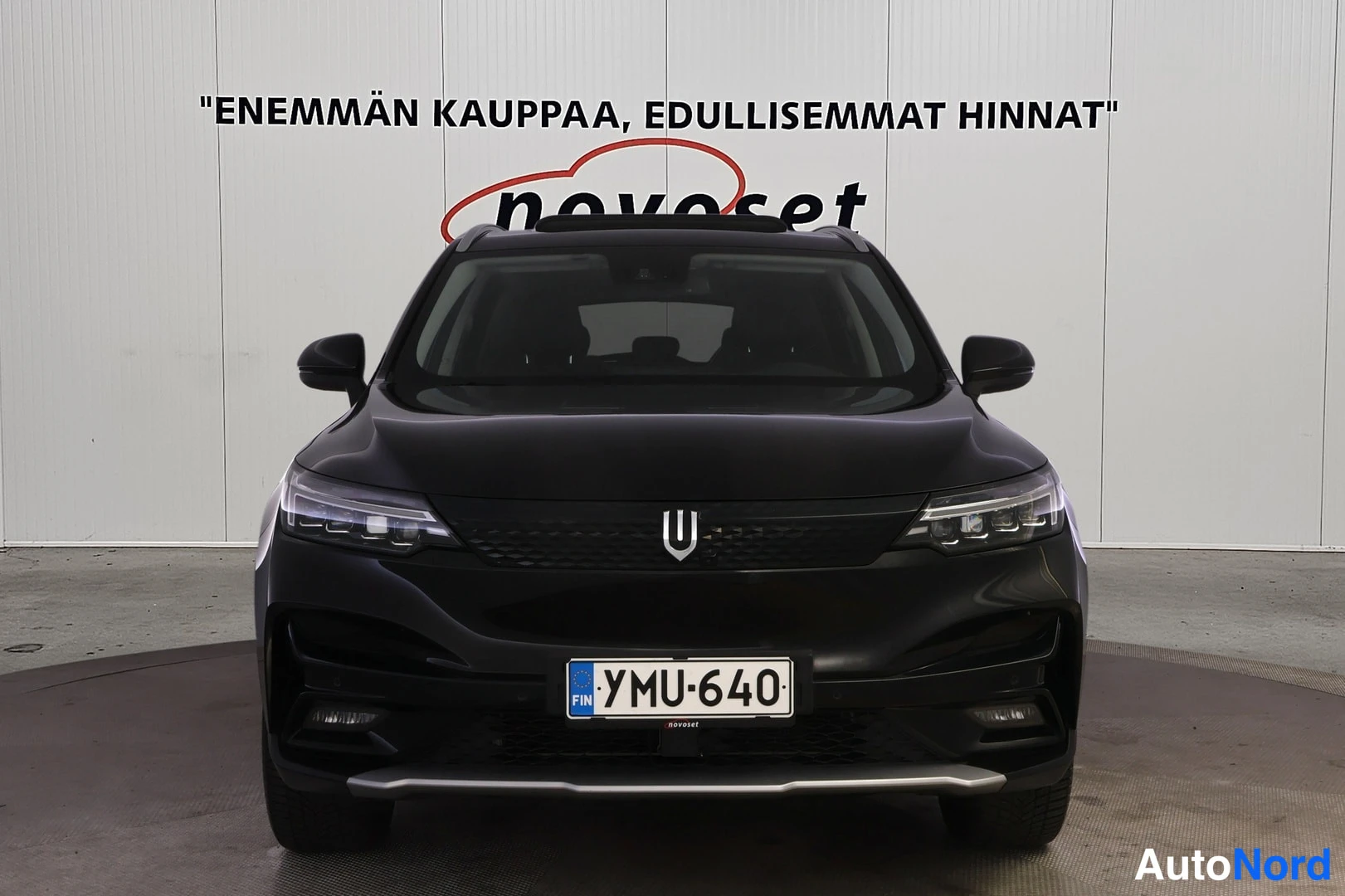 Edestä: Musta henkilöauto edestä kuvattuna, rekisteritunnus.