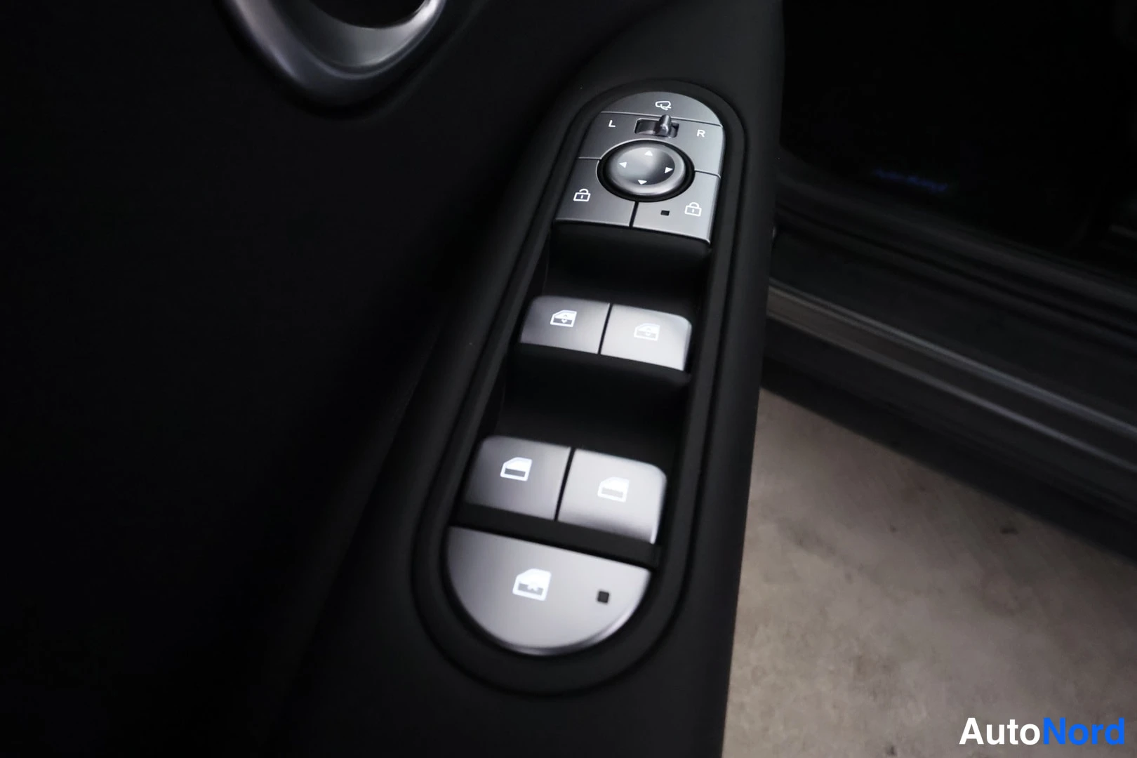 Yksityiskohta: Close-up view of the driver side door controls including window switches and mirror adjustment joystick.