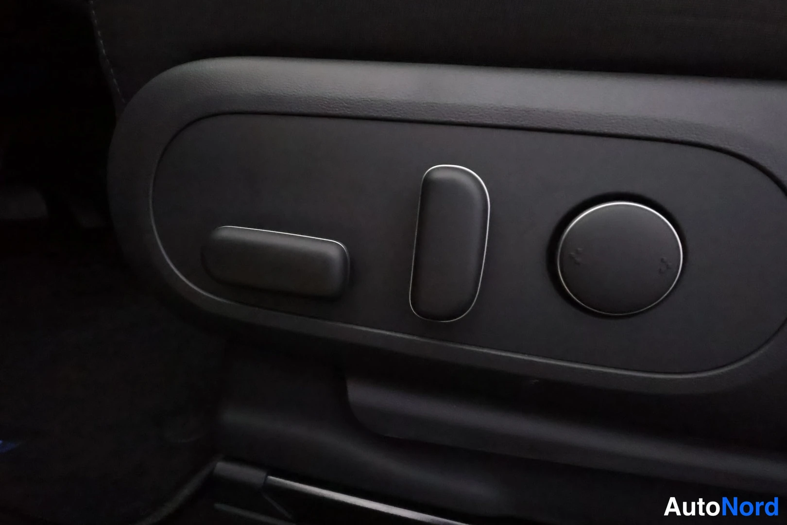 Yksityiskohta: Close-up of the electric seat adjustment controls on the side of the driver seat bolster.