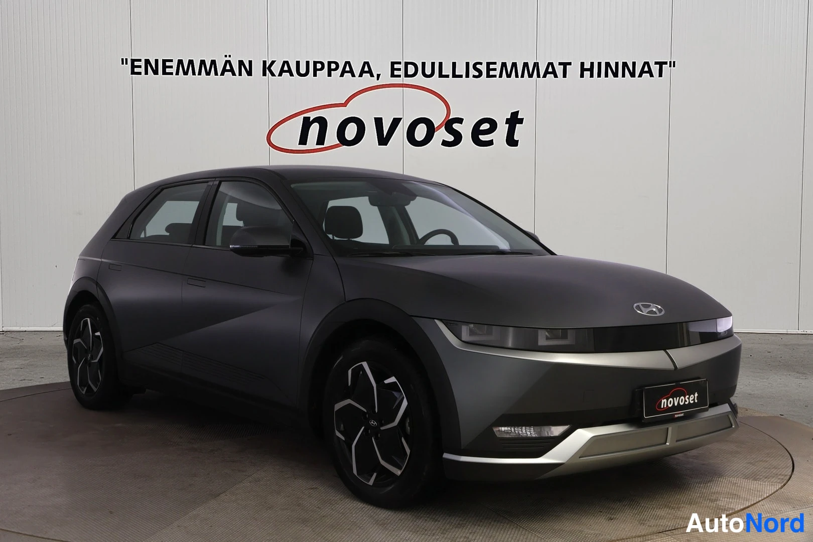 Etuviisto, nokka oikealle: Hyundai IONIQ 5:n etukulmatähys tummanharmaana autona kuvattuna studio-tyyppisesti valkoista taustaa vasten.